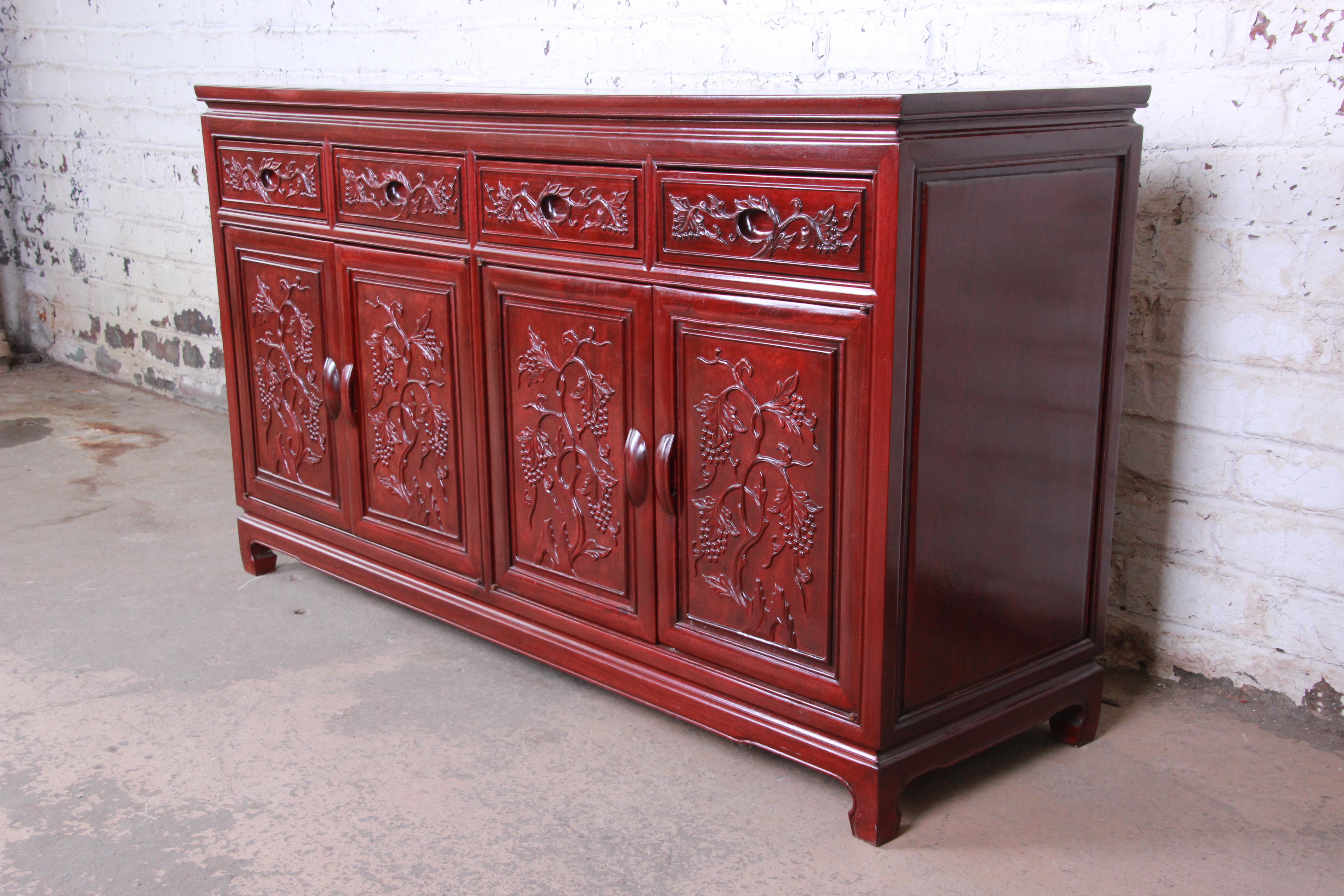 A stunning Chinese carved solid rosewood sideboard or credenza. The sideboard featured gorgeous wood grain and nice floral carvings. It offers ample storage, with four dovetailed drawers and two shelves behind four carved doors. The drawers are
