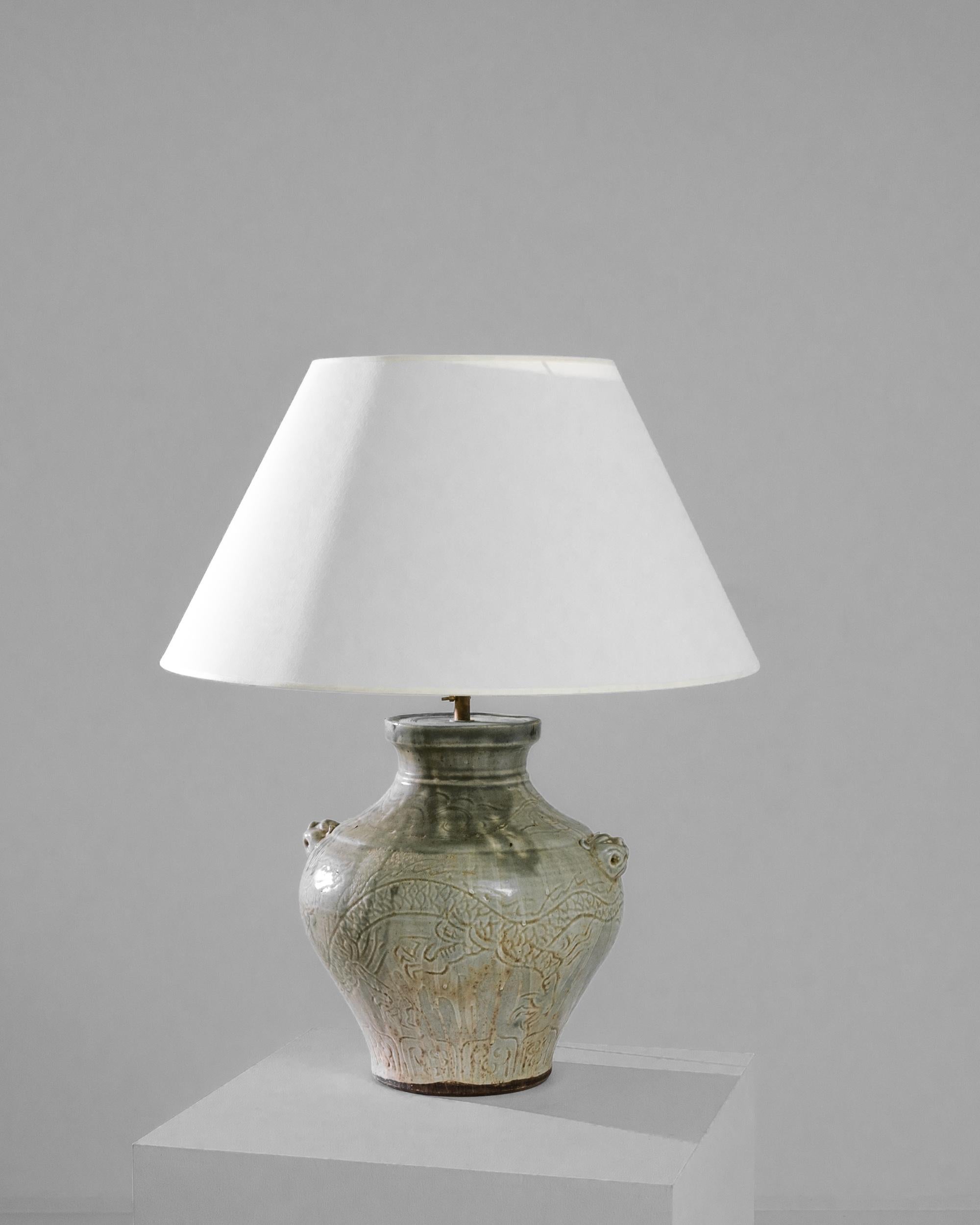 An exceptional find to inspire your collection. This vintage Chinese pear shaped vase has been adapted into a beautiful table lamp. Polished brass meets a green jade dragon glaze, enlightening your space with an uncompromising contrast. The textured