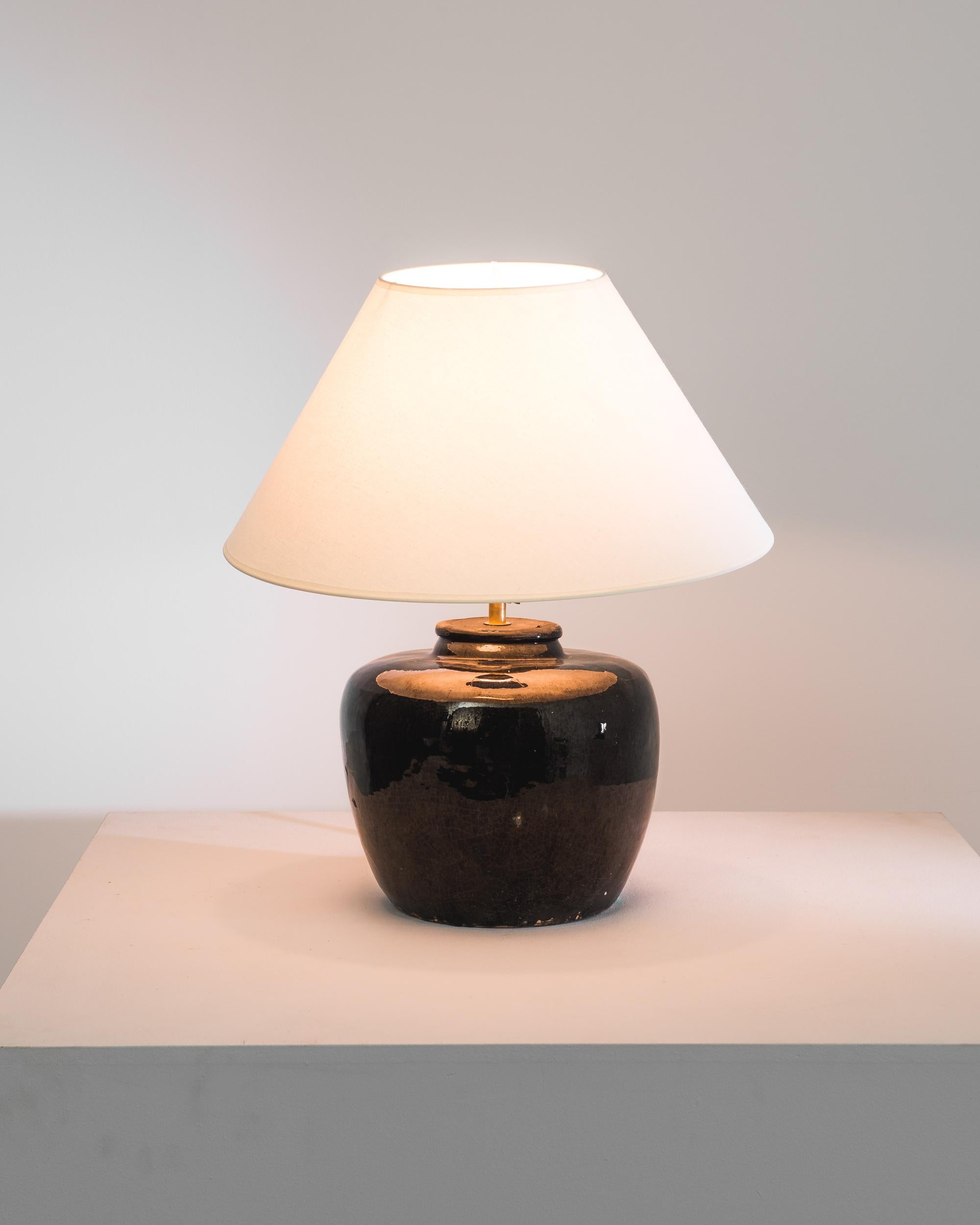 An extraordinary piece to inspire your collection. This vintage Chinese vase has been adapted into a beautiful table lamp. Polished brass meets the glossy black glaze, enlightening your space with an uncompromising contrast. The textured glazes, and