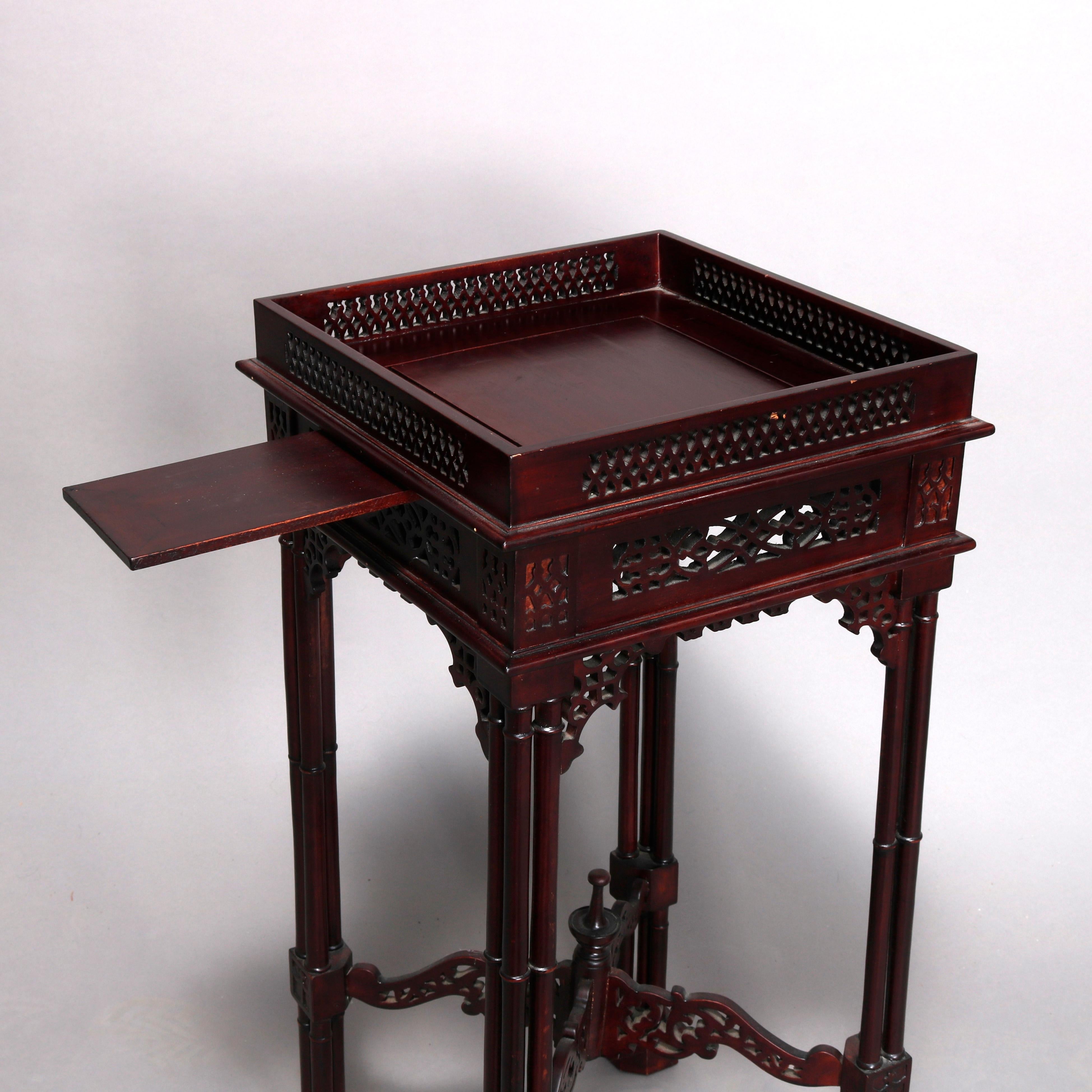 A vintage Chinese Chippendale baker school side stand offers mahogany construction with cutout gallery surmounting stand having candle slide, foliate cutout apron and corbels, raised on bamboo form legs with scroll and foliate X-form cutout