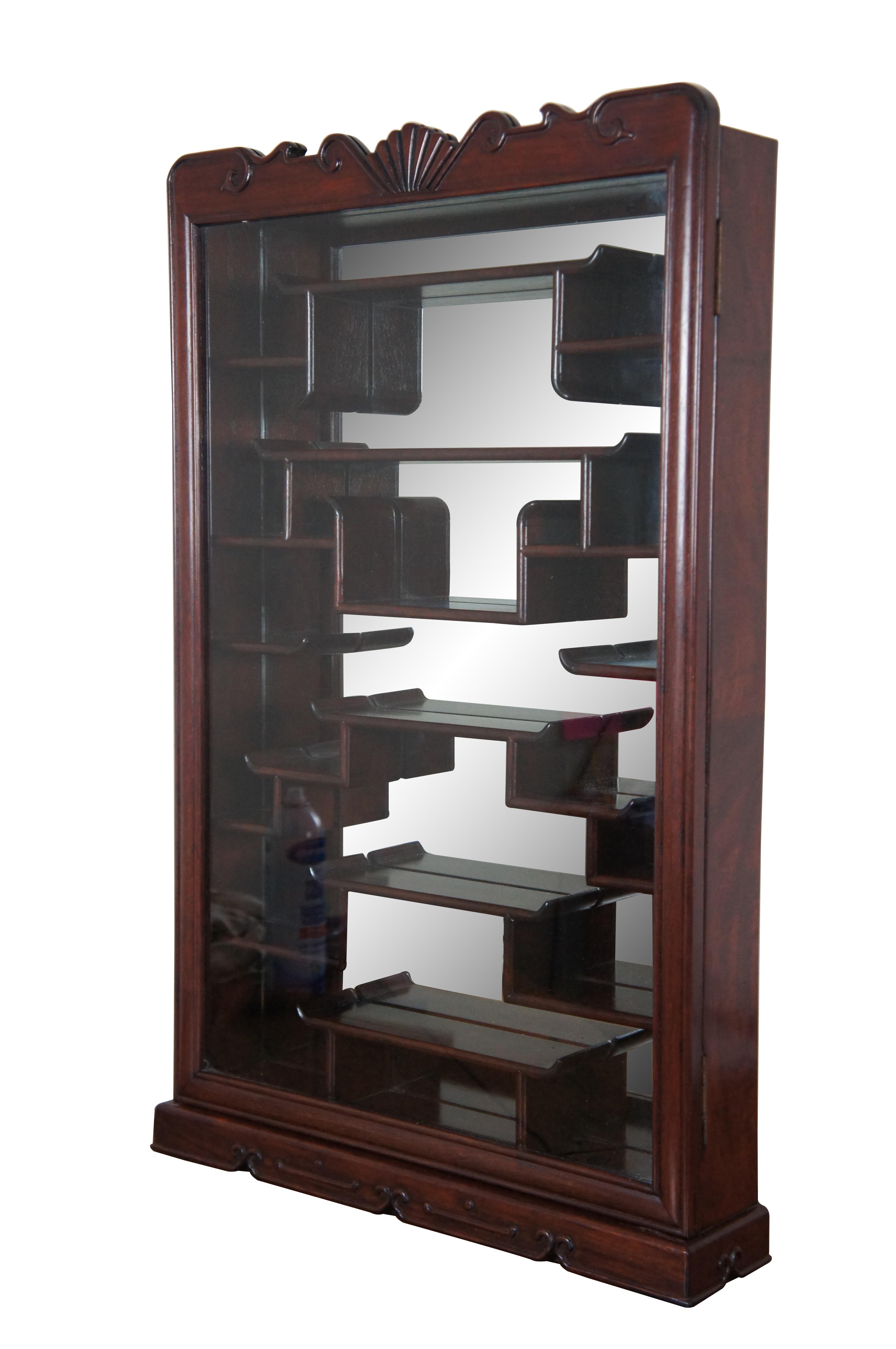 Vintage Chinese etagere wall shelf curio cabinet featuring Chippendale styling with mirrored back, carved shell top glass door and multiple display shelves for Netsuke / trinkets / snuff bottles etc.

Dimensions:
20” x 4” x 32.75” (Width x Depth x