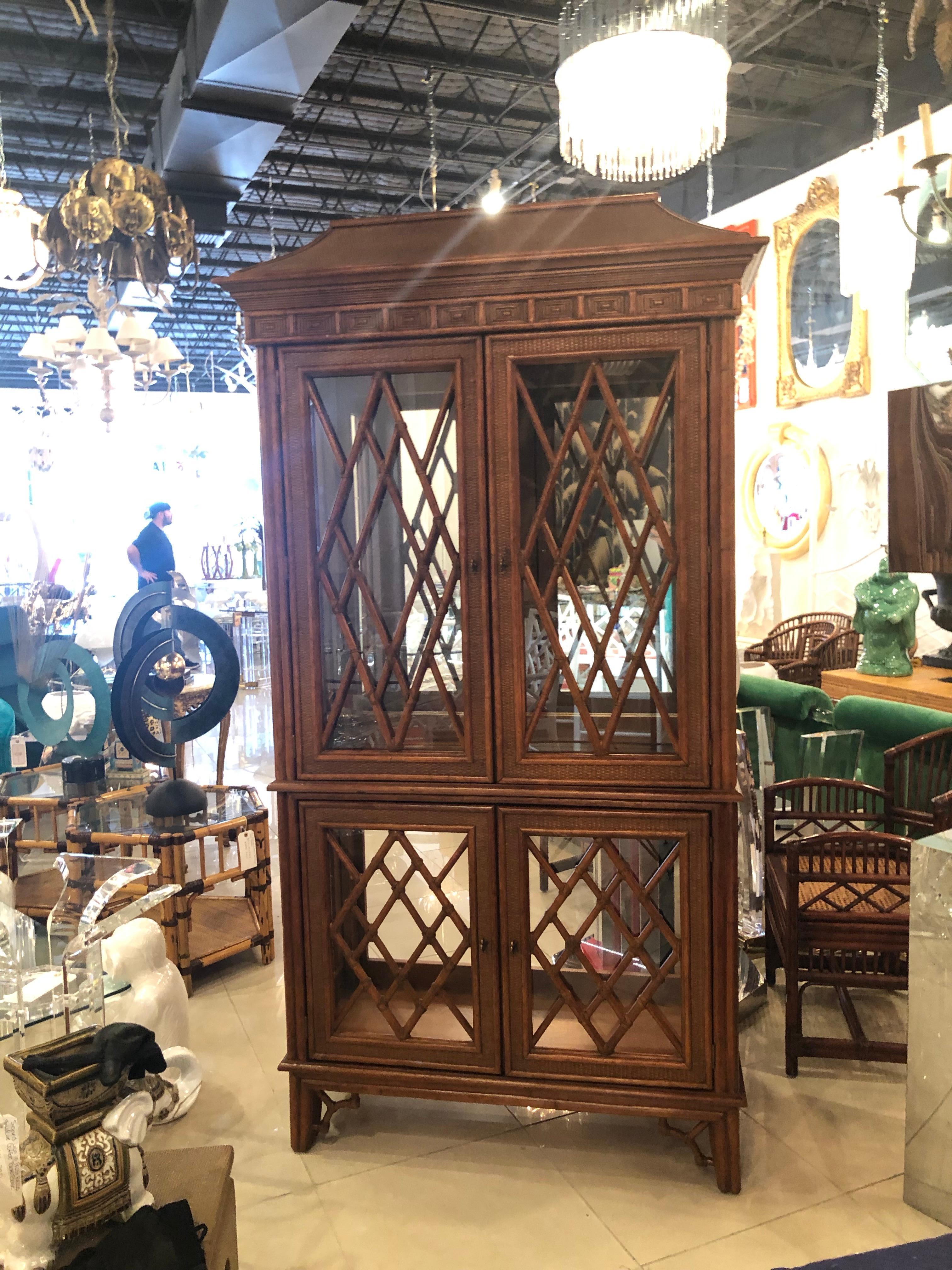 Lovely vintage Chinese Chippendale chinoiserie rattan and bamboo display cabinet. Pagoda top, 2 glass shelves on top with a bottom stationary shelf, one glass shelf on bottom and one stationary shelf. Mirror backed, light in top of cabinet that