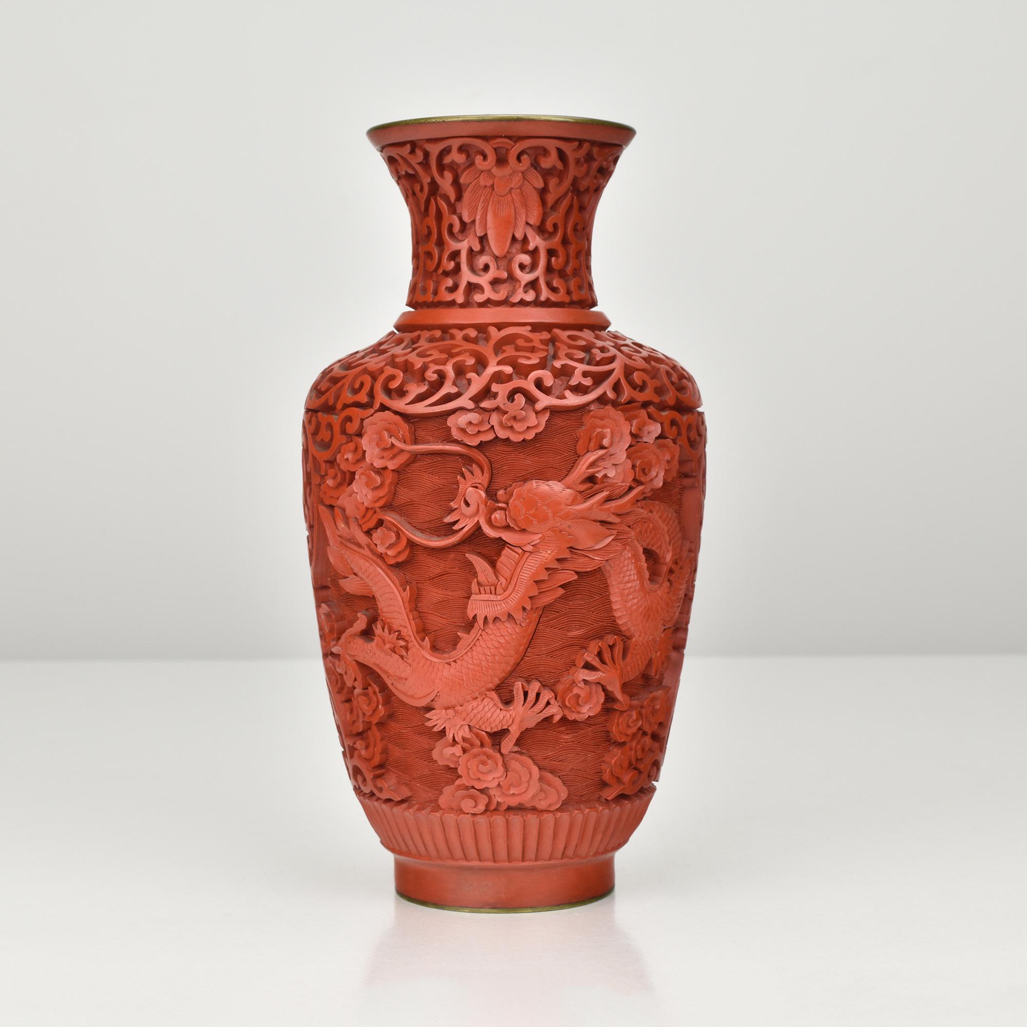 Questo bellissimo vaso cinese d'epoca in lacca cinabro presenta una decorazione eccezionalmente dettagliata intagliata a mano, con motivi tradizionali di draghi intrecciati con nuvole e volute floreali. La ricca lacca rossa mostra una profondità e