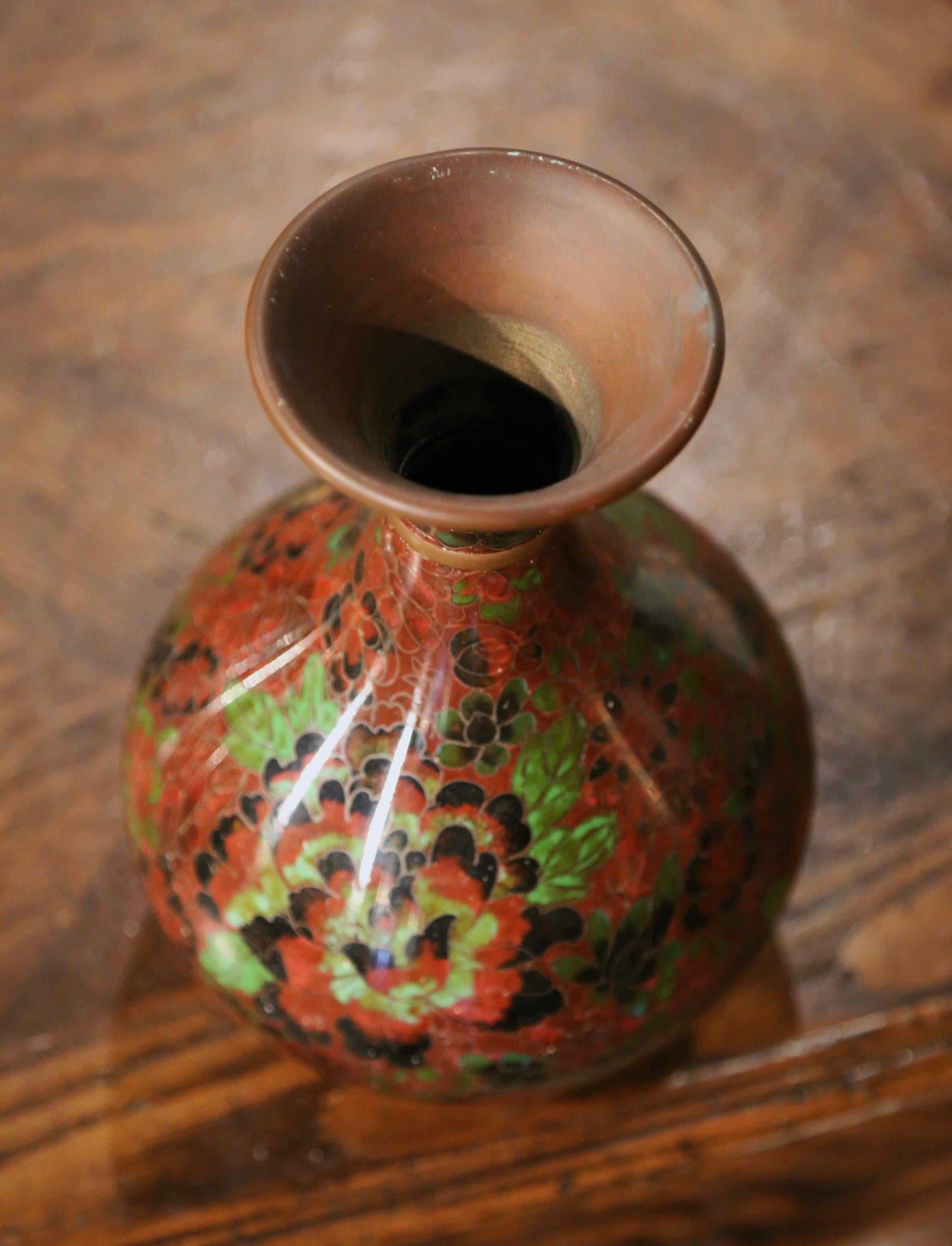 Decorate a table or a buffet with this colorful baluster vase. Created in China circa 1980, the vase sits on a carved ebonized wood stand and features floral motifs in the cloisonné technique (decorative work in which enamel, glass, or gemstones are