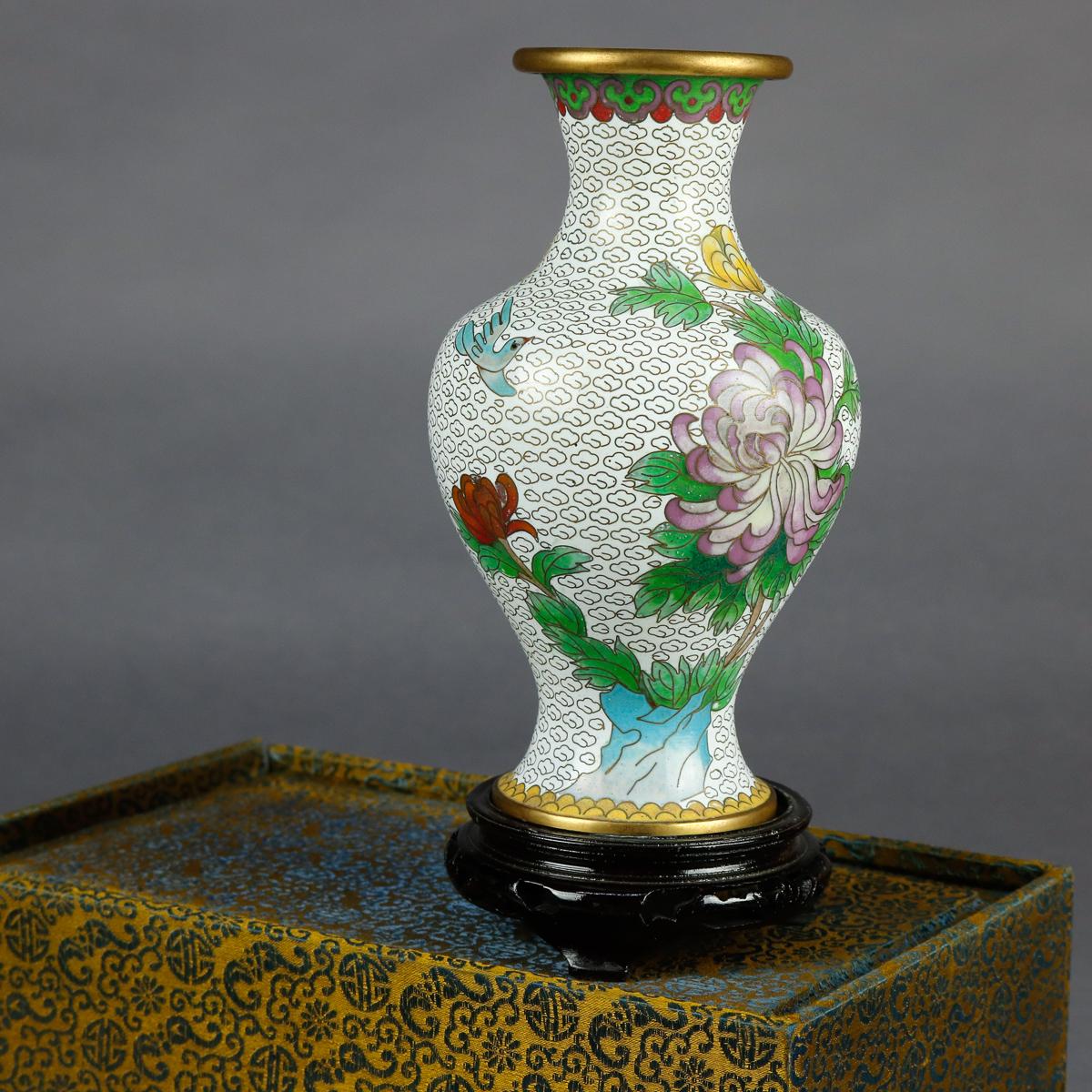 A vintage Chinese Cloisonné vase offers brass construction with hand enameled floral decoration with repeating stylized foliate bands at base and collar, includes original box and carved hardwood base, circa 1930


Measures: Vase 7.25