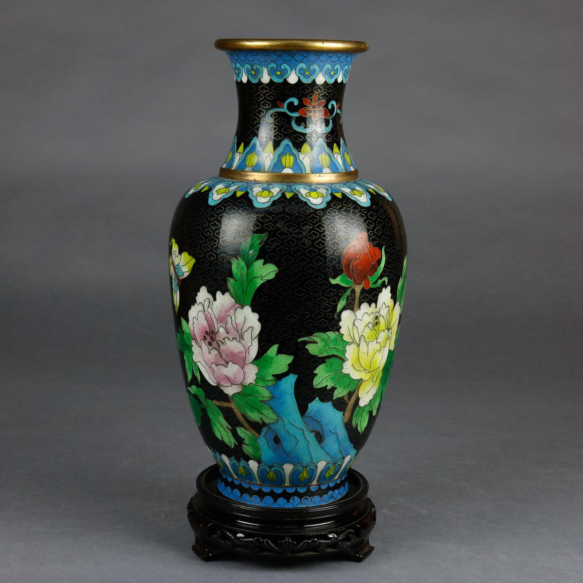 A vintage Chinese Cloisonné vase offers brass construction with hand enameled floral and butterfly decoration with repeating stylized foliate bands at base and collar, includes original box with chop mark verbiage and carved hardwood base, circa
