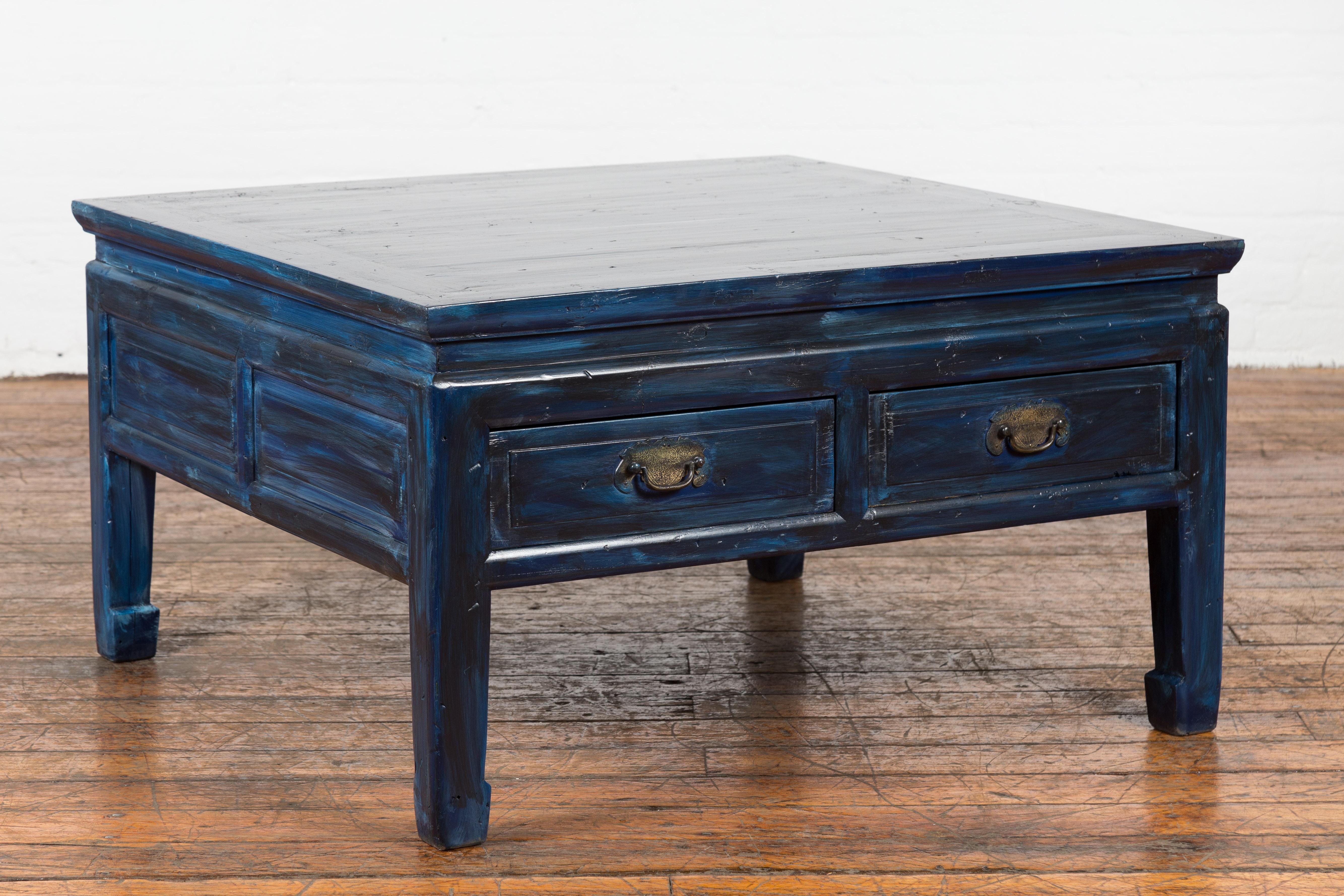 A vintage Chinese coffee table from the mid 20th century, re-lacquered with a new custom blue finish, two drawers, ornate brass hardware and horse hoof feet. This vintage Chinese coffee table from the mid 20th century is a stunning blend of