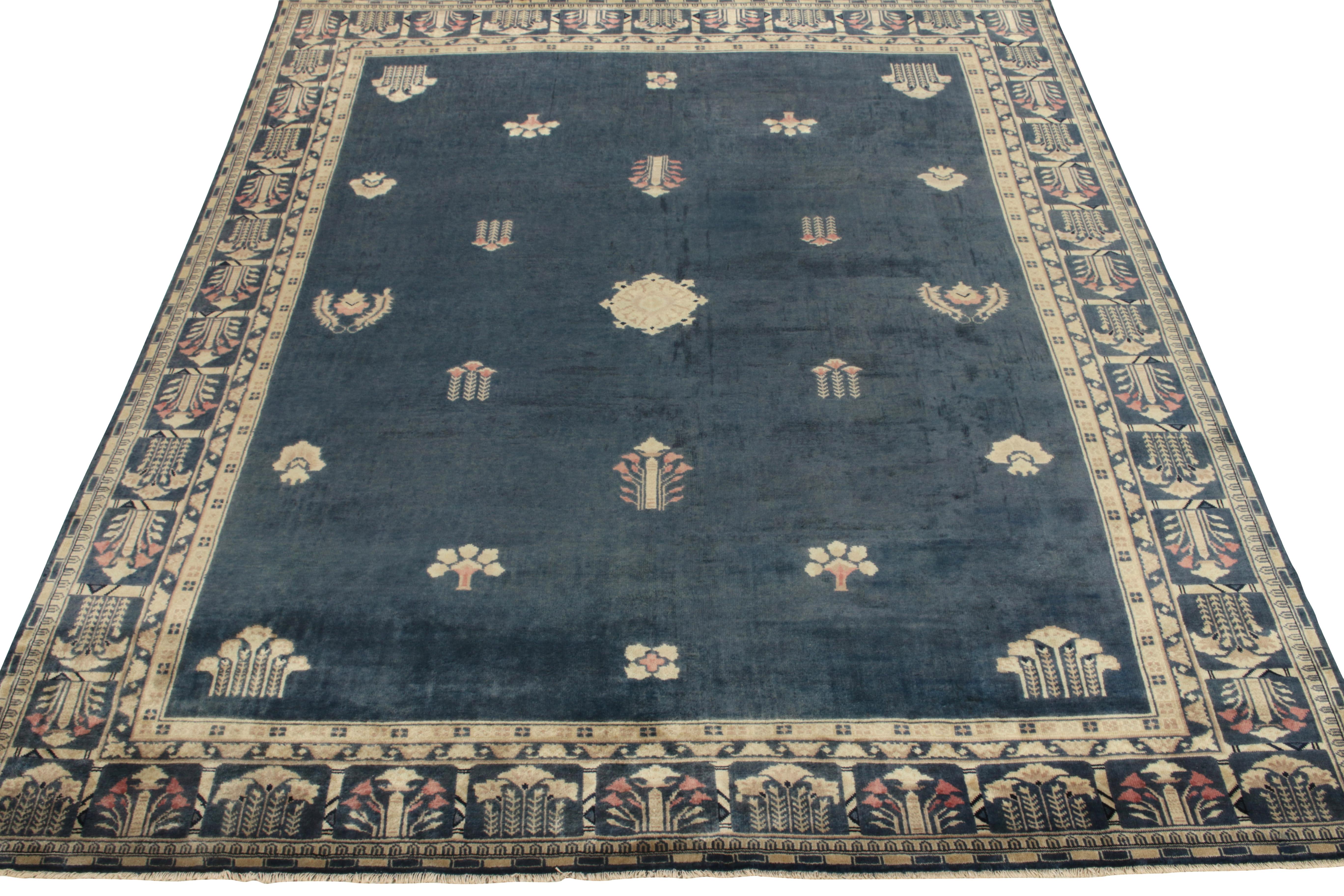 An 8x10 vintage rug exemplifying 1920s Chinese Art Deco sensibilities, featuring intricate floral patterns on field & border alike in tones of pale yellow, beige-brown & blush red on a lush blue background inviting an enticing play of light.