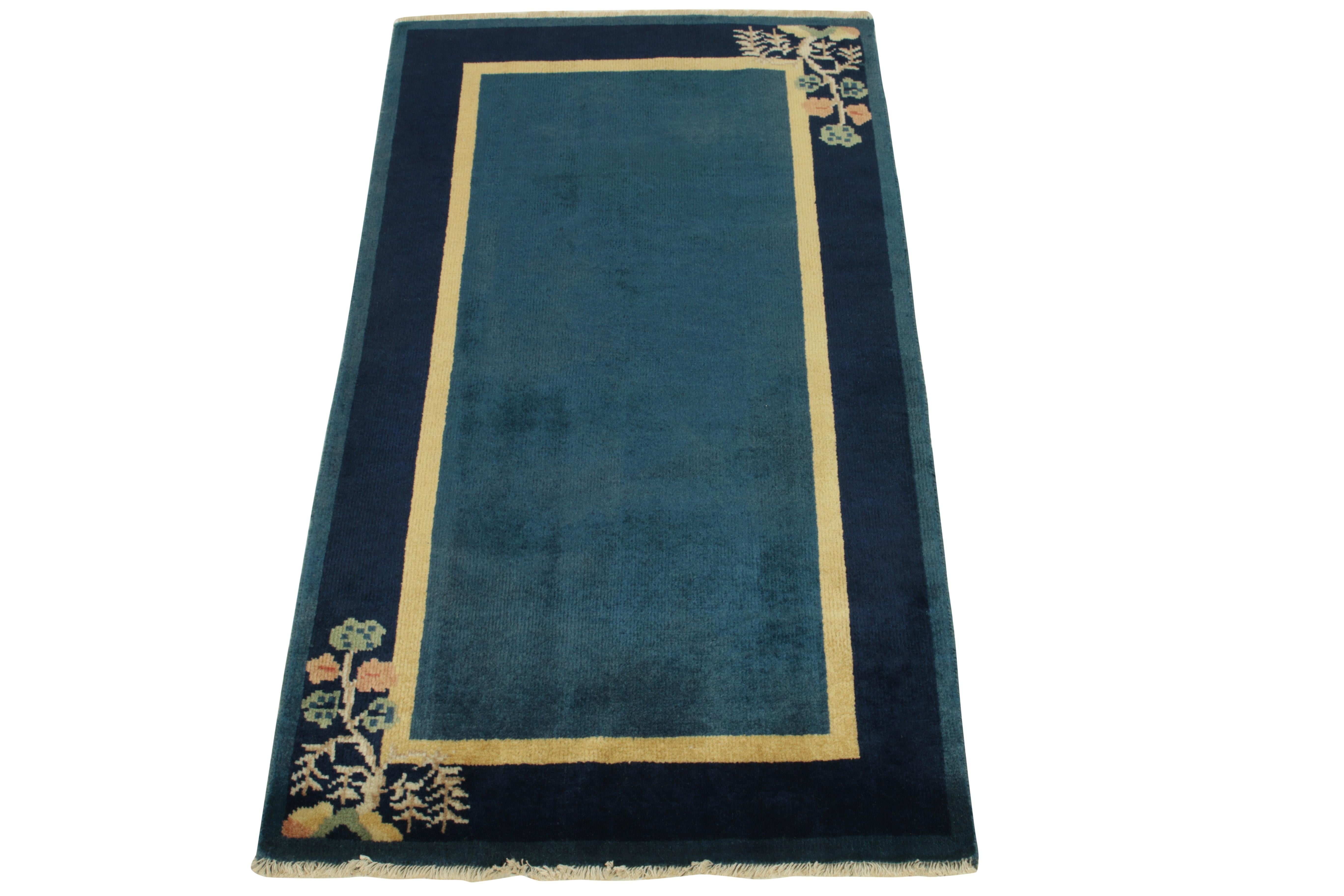 Drawing inspiration from Chinese Art Deco style of the 1920s, a vintage rug portraying an ornamental frame featuring tasteful floral patterns on a pair of corners in teal green, reddish orange & beige-brown hues—all complementing the duality of deep
