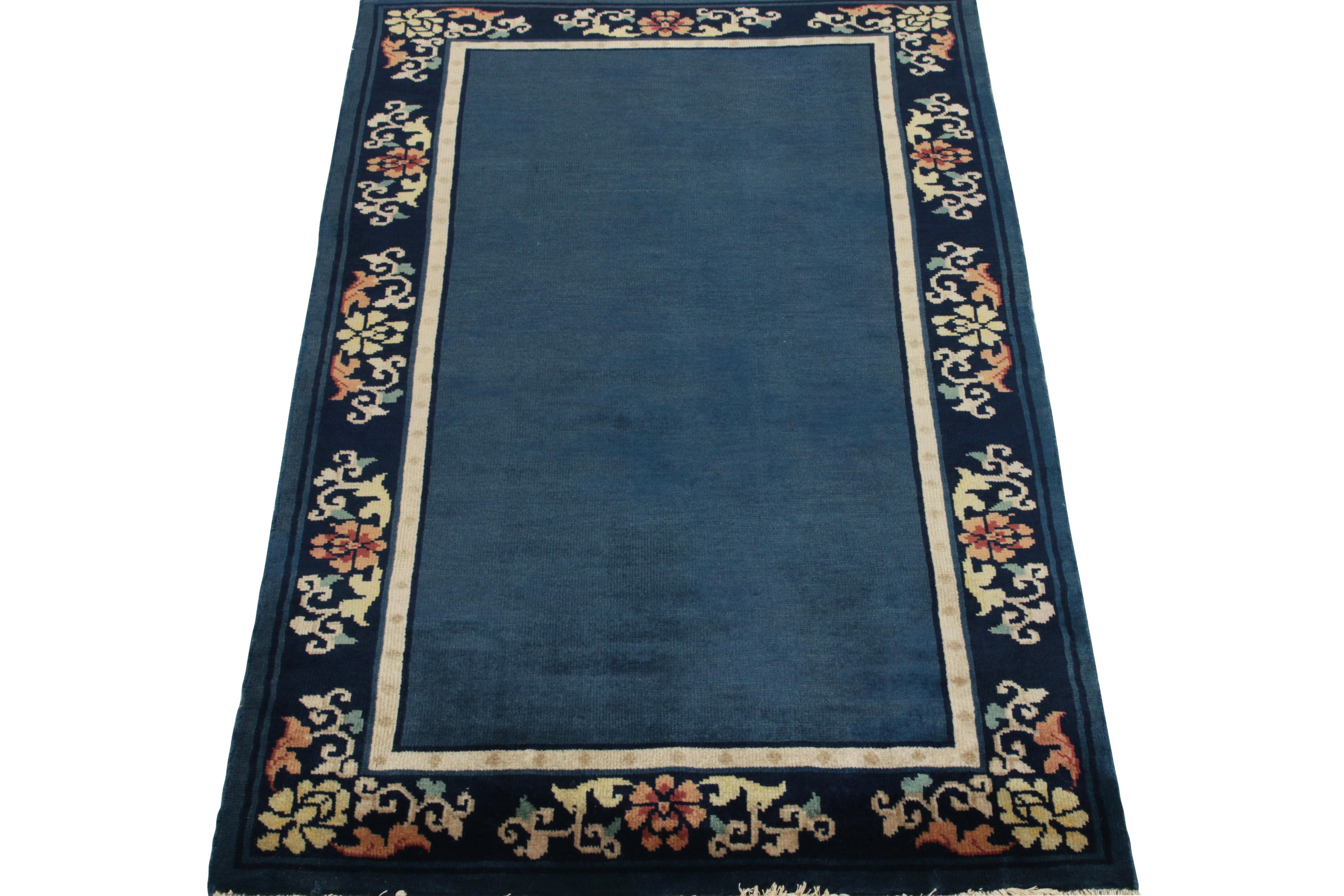 Showcasing a floral pattern in beige, teal, reddish orange & sky blue tones in the outer border, a Chinese Deco style vintage rug observing light-dark spots in blue tones connoting a very classic appeal of the 1920s. Further enjoying a fine light