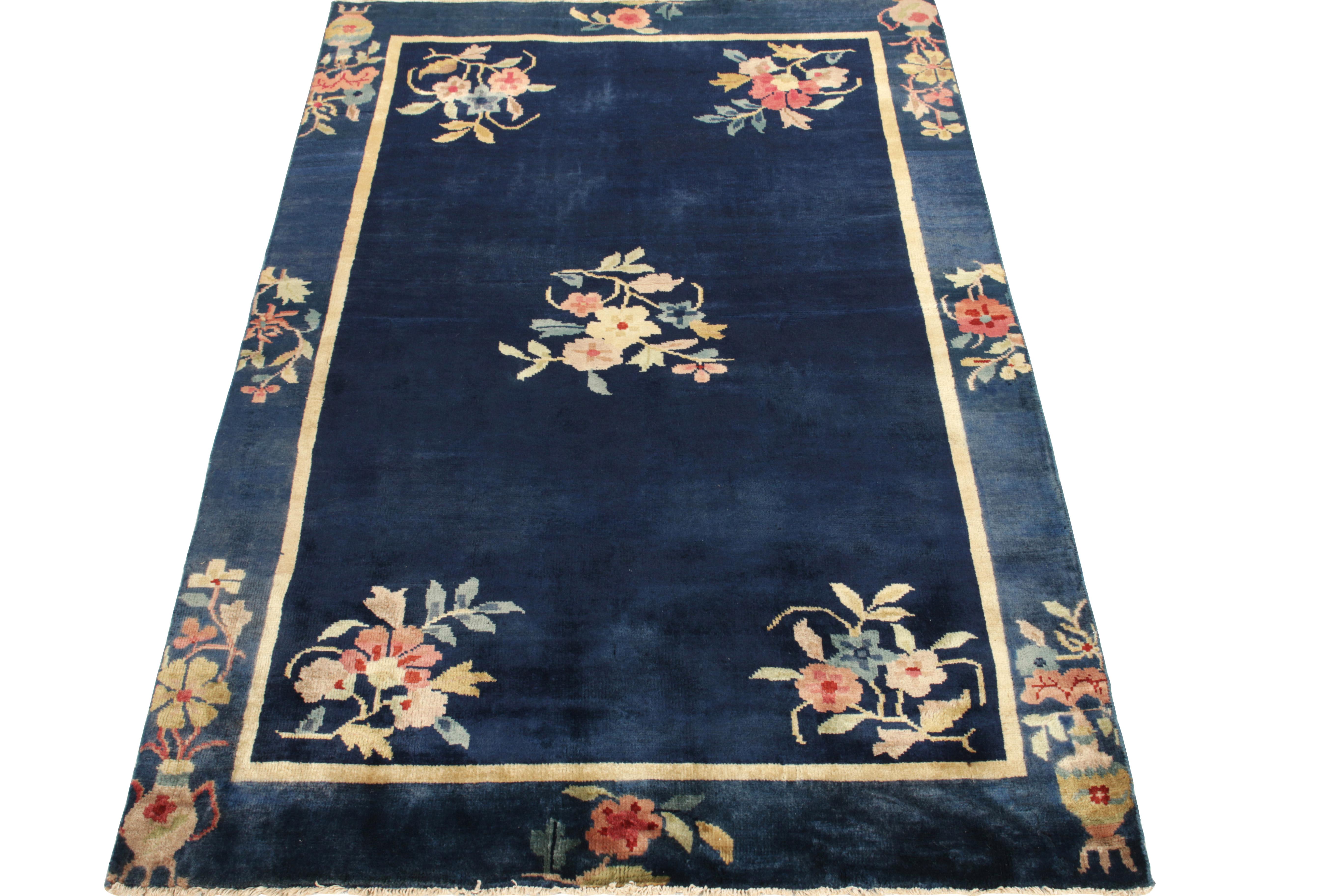 Celebrating the Chinese Art deco style of the 1920s, a 4x6 vintage rug from Rug & Kilim’s newest line of modern classics—carrying a montage of vase pictorials & floral patterns in red, baby pink & lime green decorating the the deep blue border &