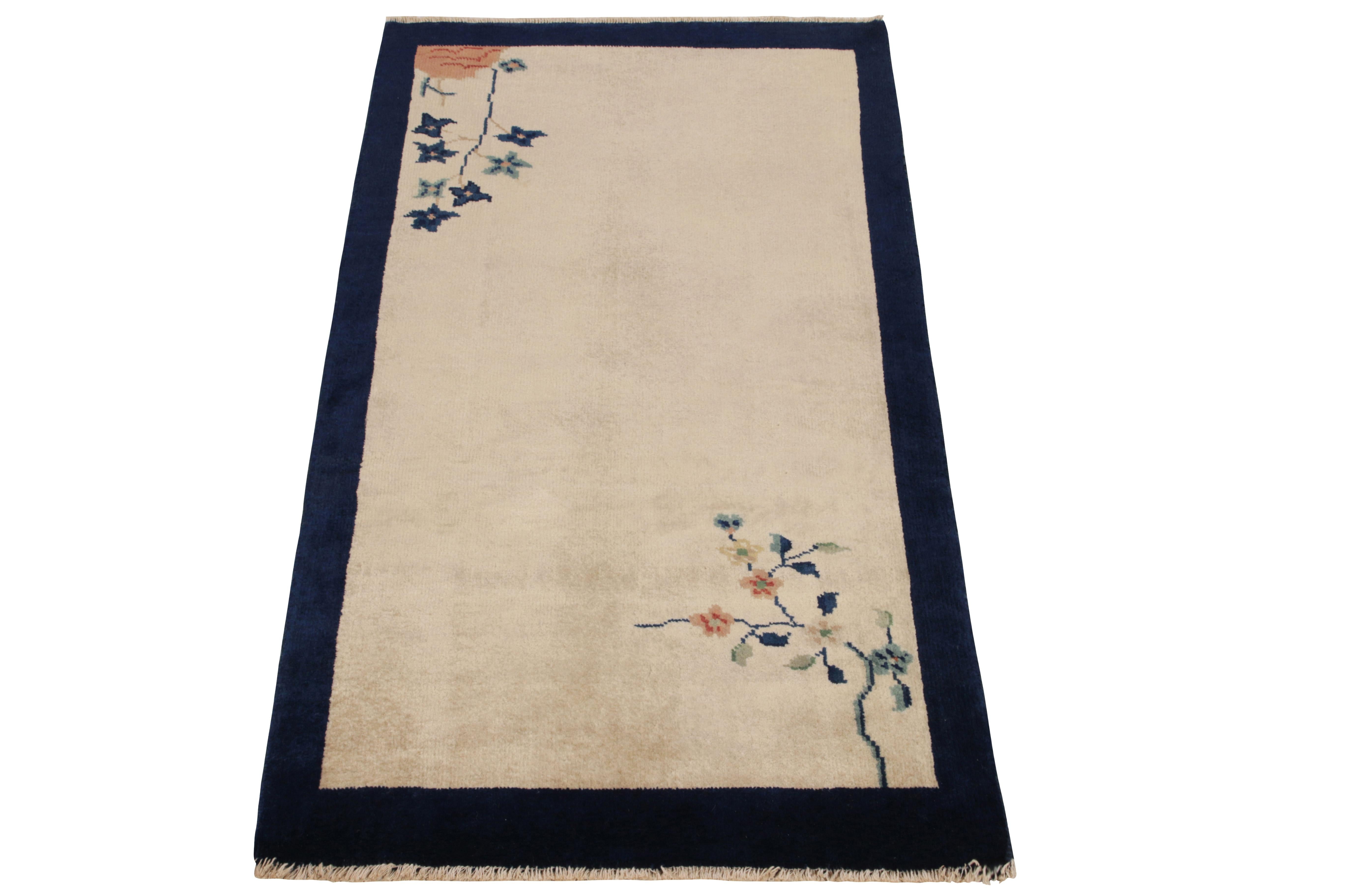 Hand-knotted in wool, this 2x4 vintage ode to Chinese art deco rugs of the 1920s features flowers flourishing in delicious hues of rich blue, reddish orange & pastel green in diagonal corners of the inner border highlighting the minimalist approach