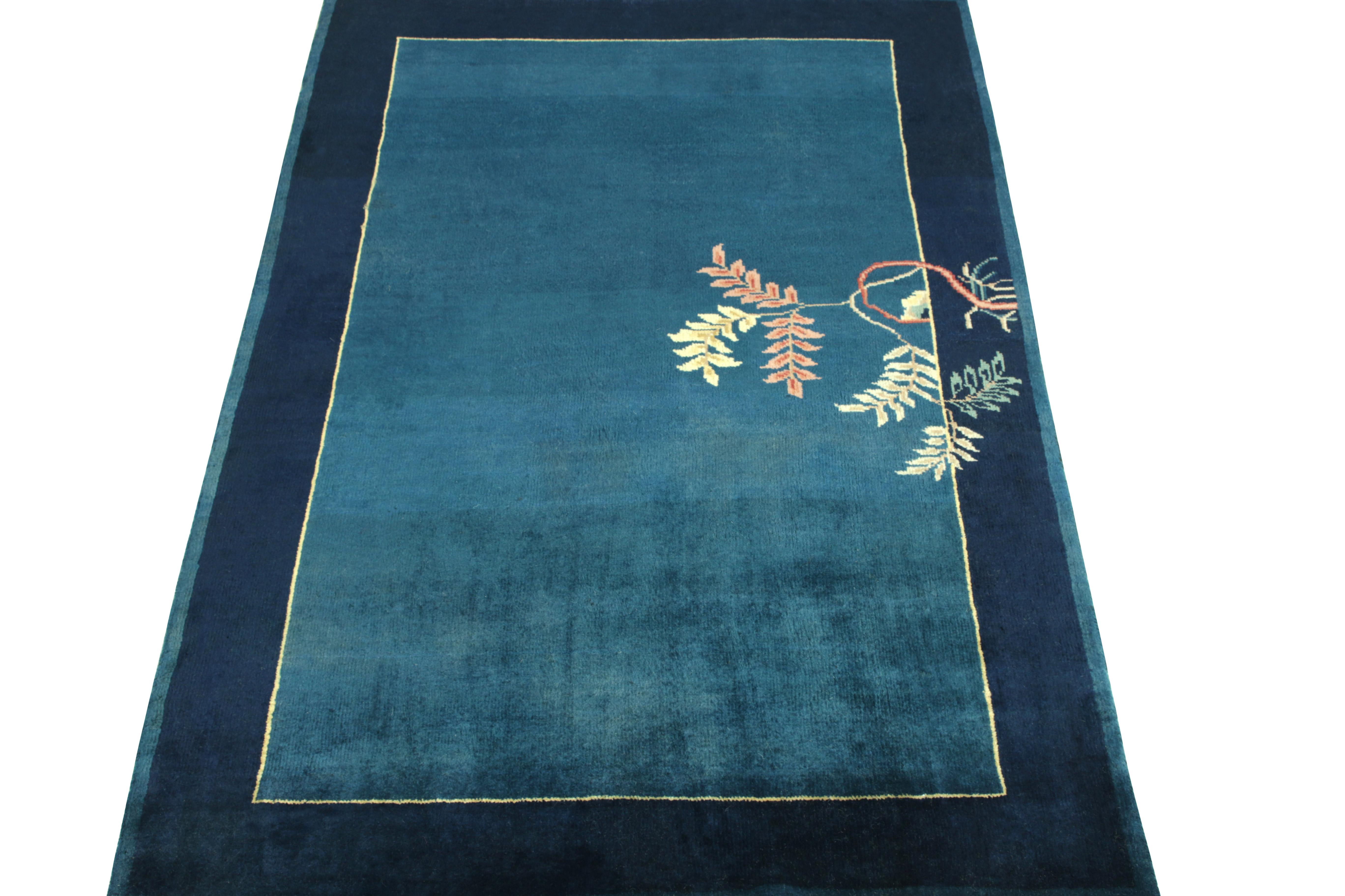 Favouring a swaying floral pattern in off white, peach, yellow & teal from the border to the field, a Chinese deco style vintage rug observing light and dark spots in tones of deep blue—connoting a very classic inspiration of the 1920s with fine