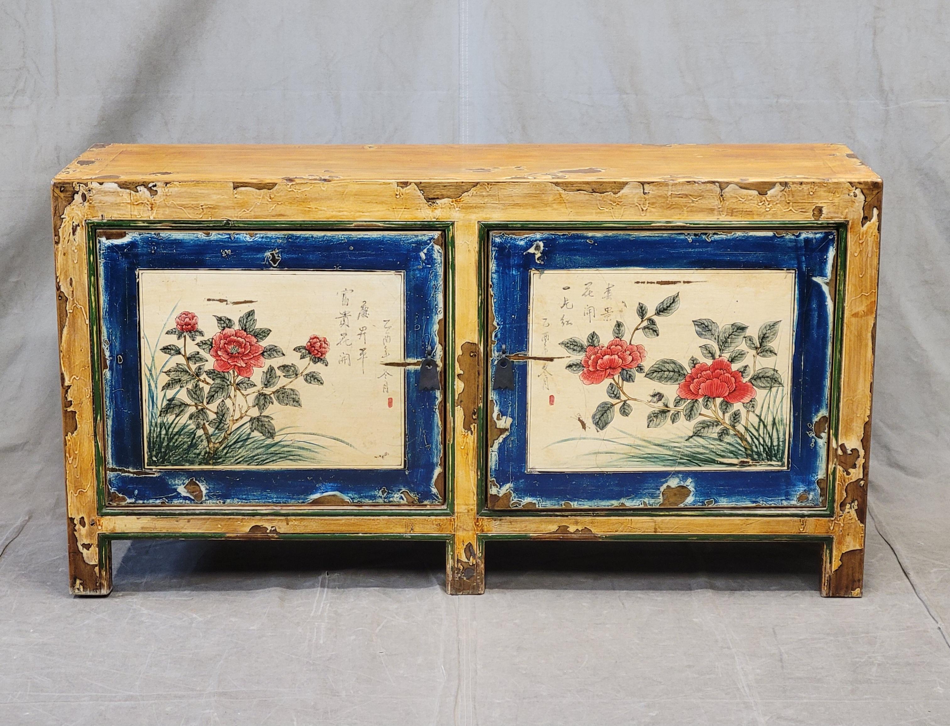 A charming vintage Chinese lacquer console cabinet in gorgeous shades of ochre, blue, white, red and green. The painted floral door panels are accented with Chinese writing. Note the distressing in the lacquer finish, see photos, that add a rustic