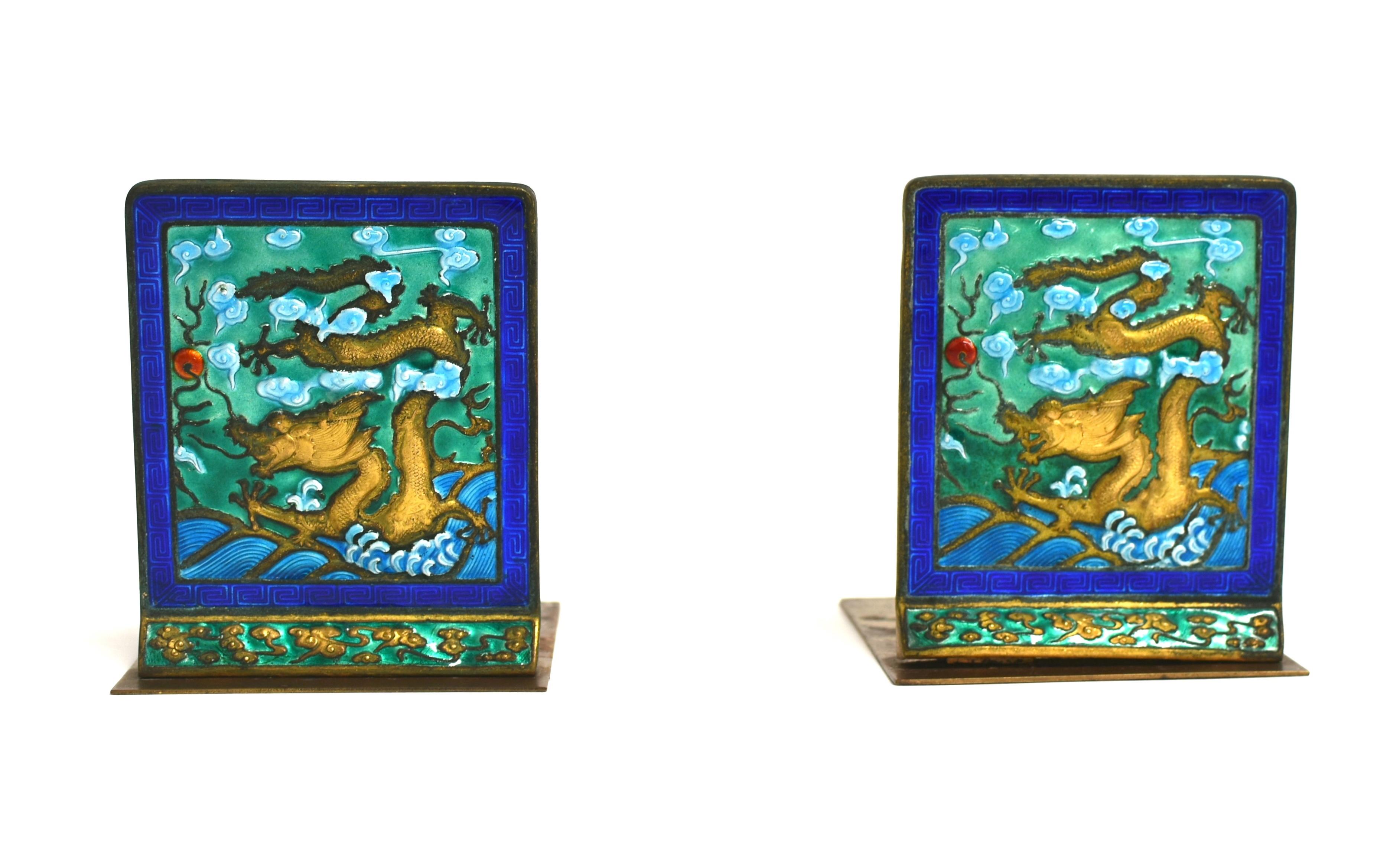 From a private collection, a pair of spectacular solid brass enameled bookends. The featured dragon merging from ocean waves where they meet the clouds, has all five of his talon open in pursuit of its subject, a fire ball. The head strains forward