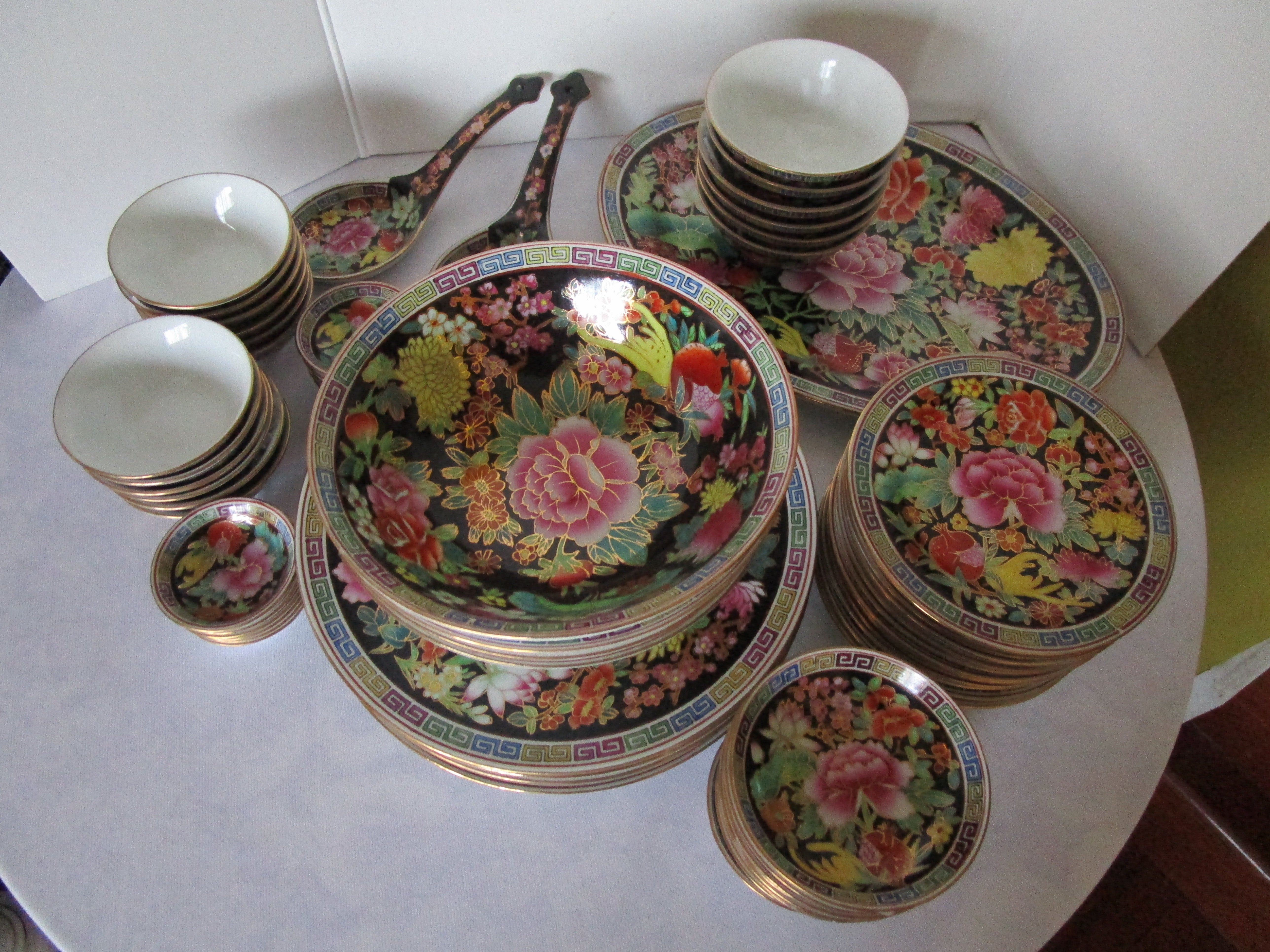 This set of assembled plates, bowls, serving items and spoons is a visual feast and a profusion of flowers on black ground and detailed gilt hand painting. The pieces are in very good condition without cracks or chips.
There are 12 bowls: 4