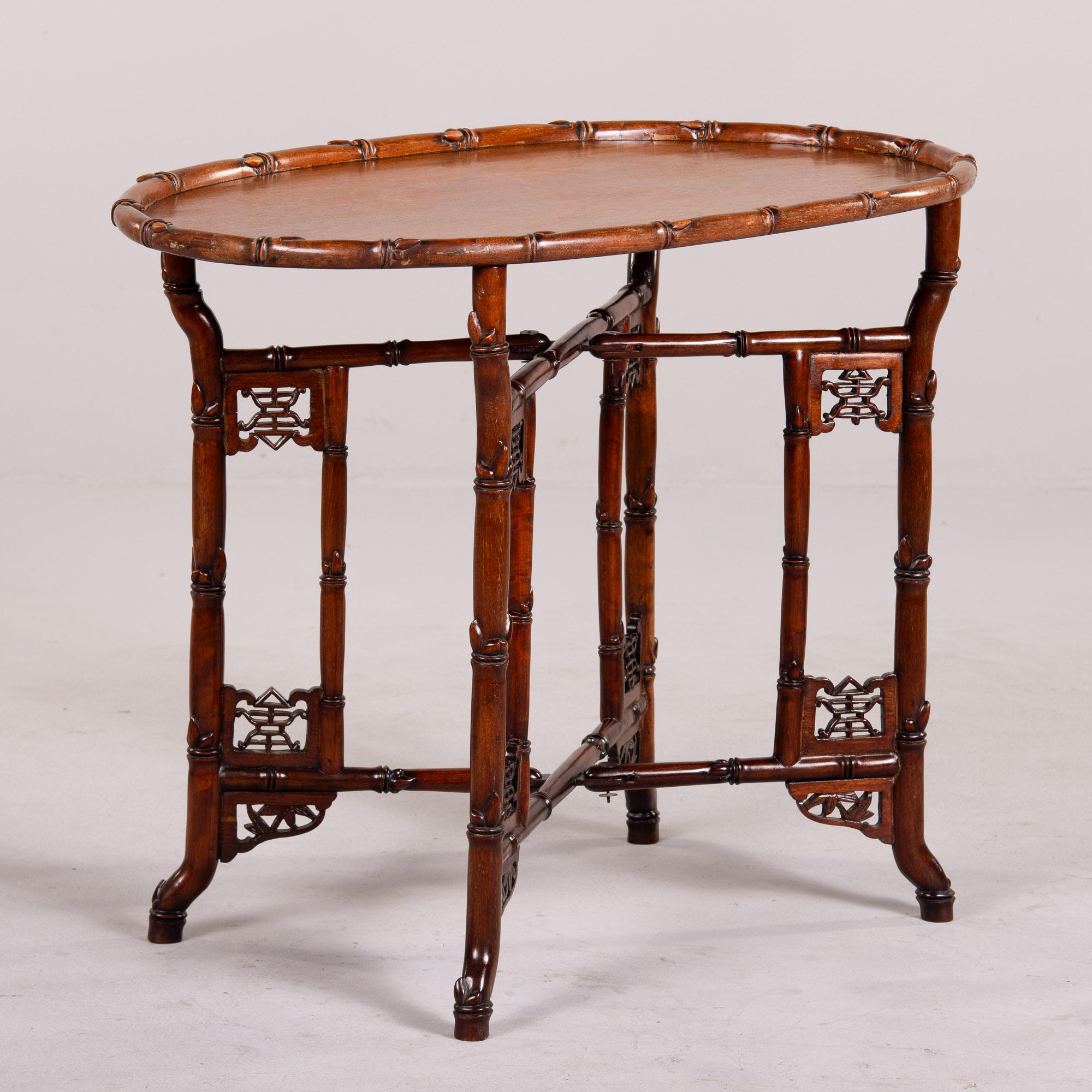 Found in England, this oval Chinese tray table dates from the 1940s. Table top is a removable oval tray with a faux bamboo outer rim. Base has decorative open work details and folds closed. Because the top can be removed and the base can be folded