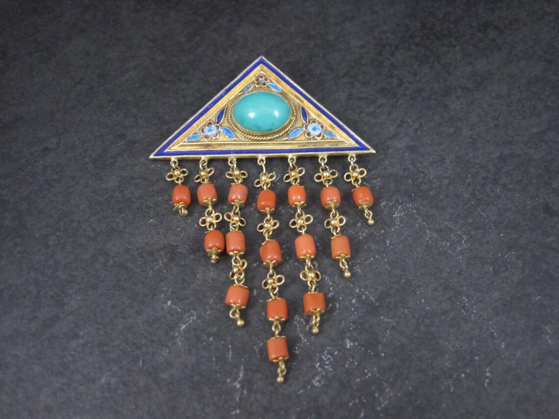 This gorgeous Chinese brooch is gold vermeil over silver.
It features a beautiful turquoise stone accented by natural coral and delicate enamel.

Measurements: 2 1/8 by 3 1/4 inches

Marks: Silver

Condition: Excellent