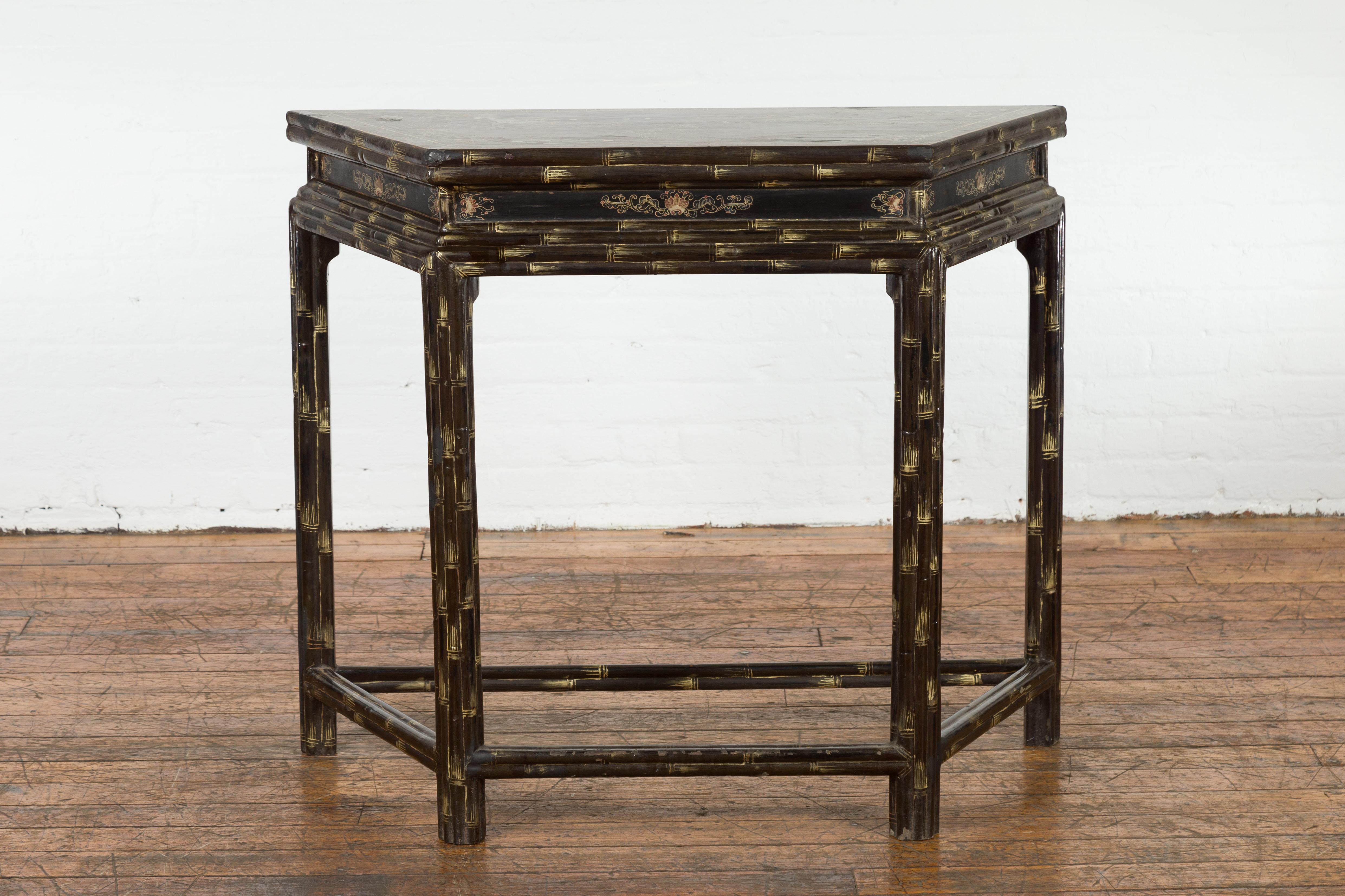A vintage Chinese demilune console table from the Mid-20th Century with faux bamboo, dark brown patina and hand painted décor. Created in China during the Midcentury period, this demilune console table features a trapezoid top, adorned with a
