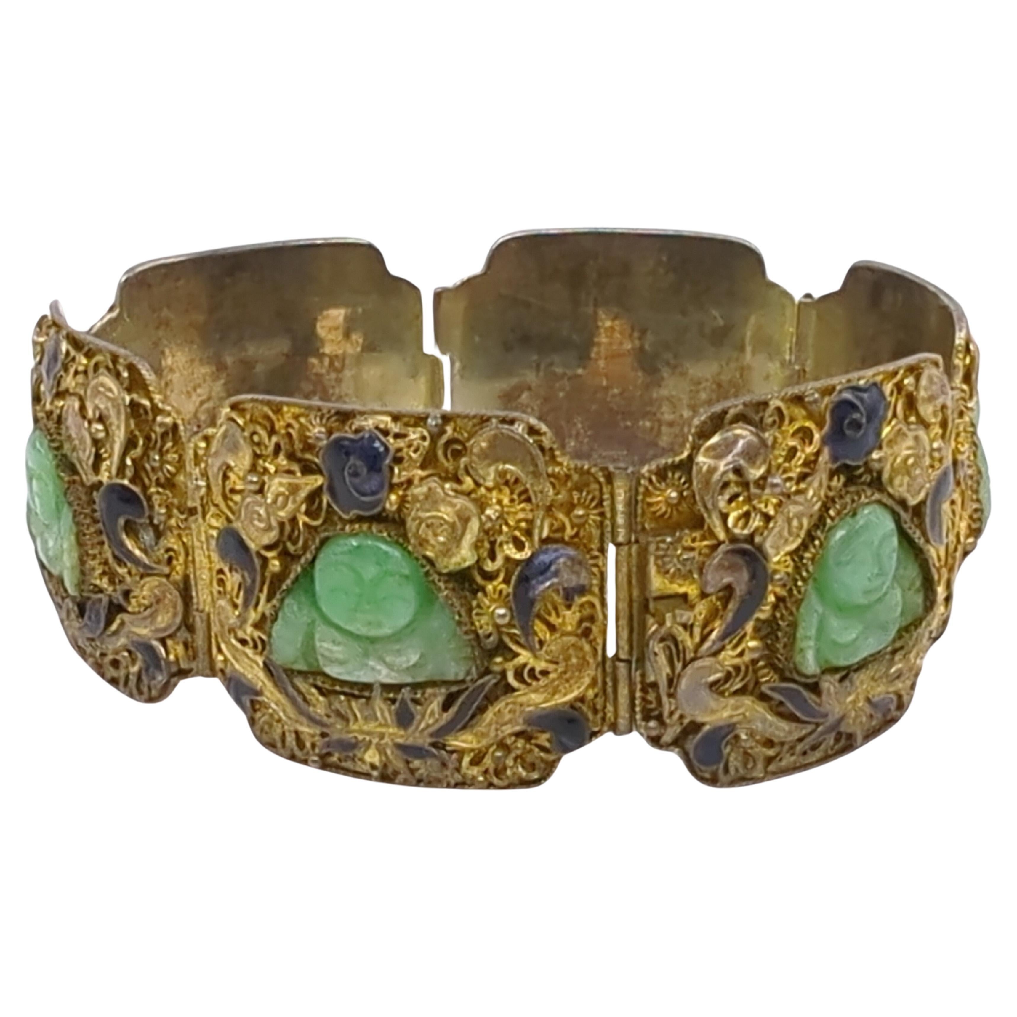 This exquisite mid-20th-century bracelet is a masterful blend of craftsmanship and symbolism, featuring six links of gold-plated silver filigree, each inset with a green jade seated Buddha. The Buddhas, carved with smiling faces, serve as the focal