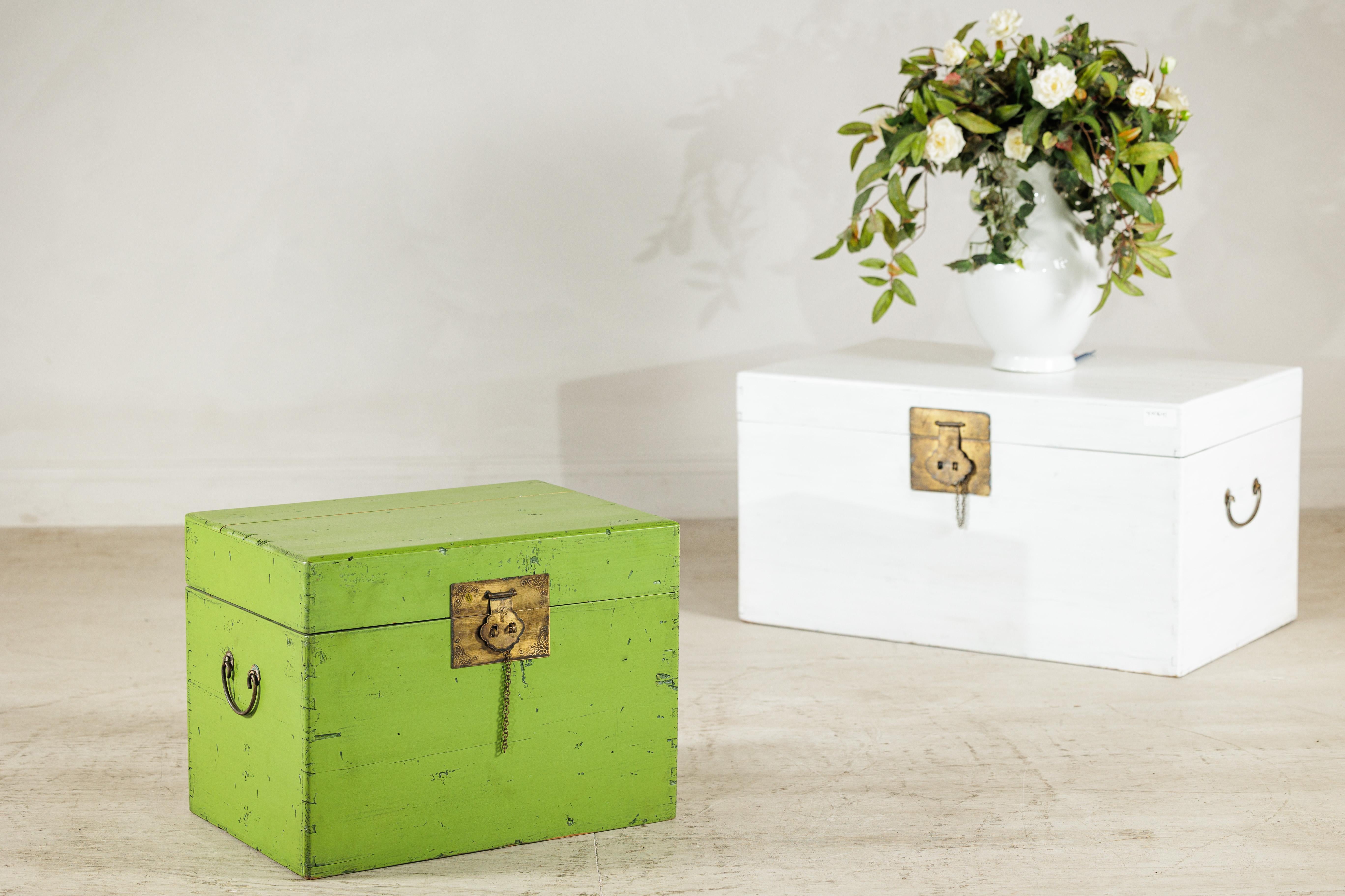 Une malle chinoise vintage avec une finition laquée verte accentuée par des ferrures et des poignées latérales en laiton. De forme rectangulaire, le coffre s'ouvre par le haut sur des charnières en laiton et est équipé d'une plaque de serrure