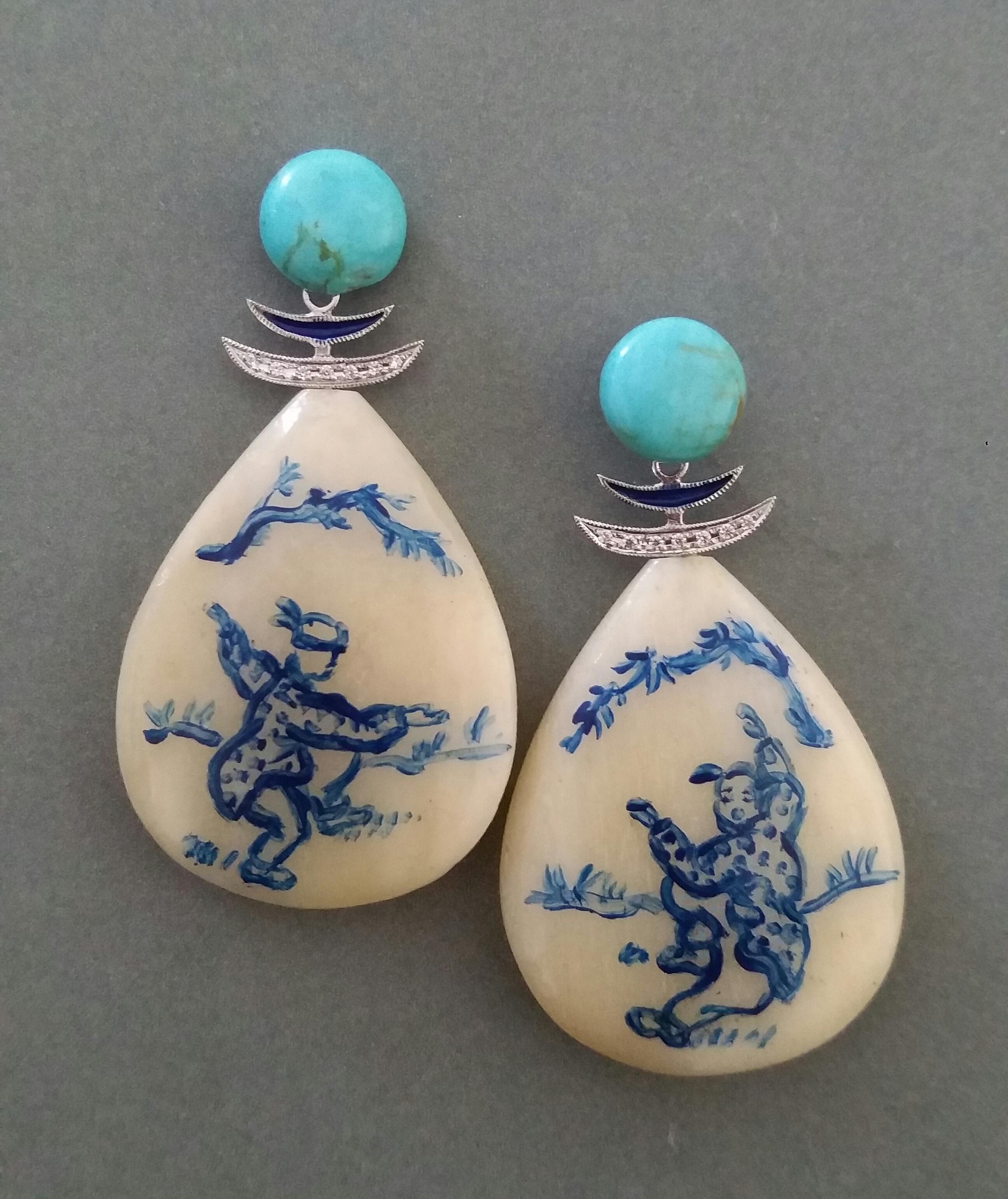 Vintage drop shape hand painted cow bones flat drops depicting 2  young chinese boys playing in a open space,suspended from 2 round Turquoise cabochons 10 mm in diameter,in the middle we have 2 white gold parts with diamonds and blue Enamels

In