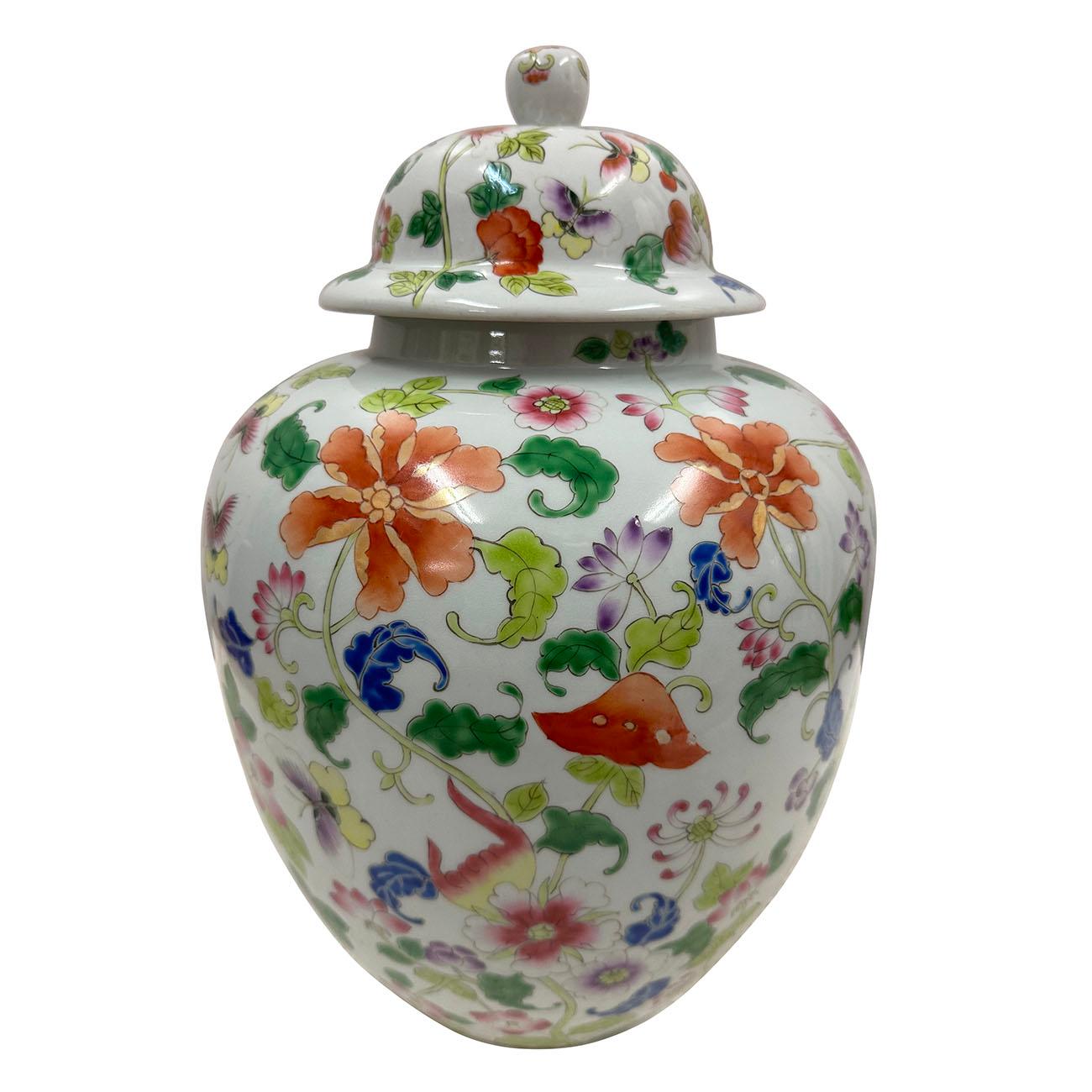 Ce grand pot à gingembre en porcelaine avec couvercle est orné d'un superbe motif peint à la main de fleurs, de vignes, de feuilles et de papillons. Belles couleurs de plantes roses, orange, vertes, jaunes et bleues sur un fond blanc. Le travail sur