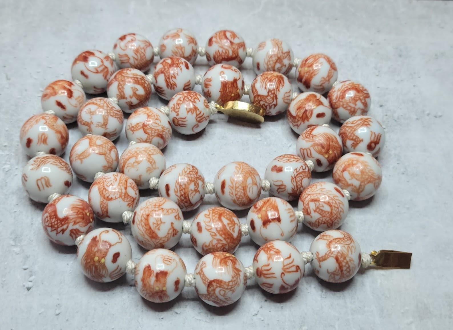 This vintage Chinese porcelain bead necklace features 37 beads with russet orange designs hand-painted on a light-colored whitish hand-knotted silk 