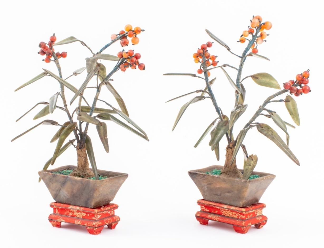 Vintage Chinese hardstone Sea Buckthorn (Shaji, or Hippophae rhamnoides) plant sculptures, each with nephrite leaves wired to a trunk sprouting Cinnamon Jade berries in agate pots, together with red silk covered stands. 

Dealer: S138XX
