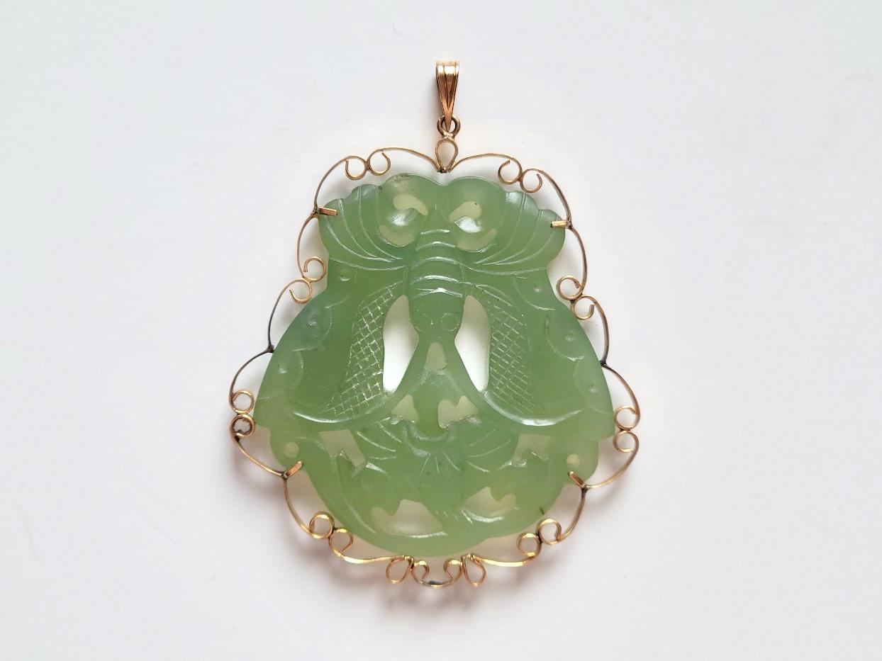Superbe pendentif ancien en jade vert sculpté à la main qui a été décoré vers le milieu du 20e siècle en or 585 (14k). Le jade lui-même date approximativement de la fin de la dynastie Qing, peut-être plus ancien.

Le jade transparent est percé et