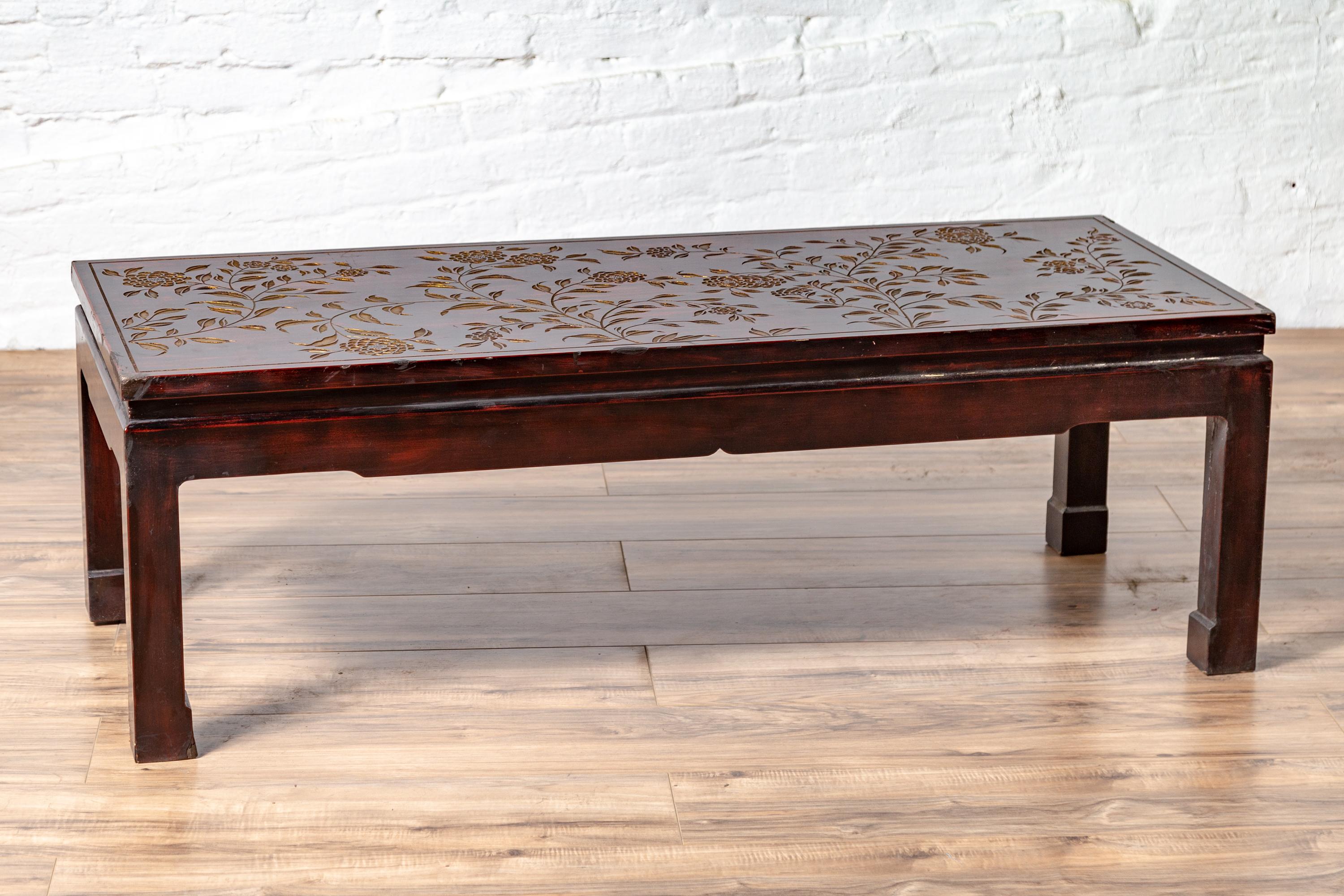 A Chinese vintage lacquered coffee table from the mid-20th century, with carved gilt floral motifs. Born in China during the mid-century period, this exquisite coffee table attracts our attention with its subtle charm and delicate décor. Presenting