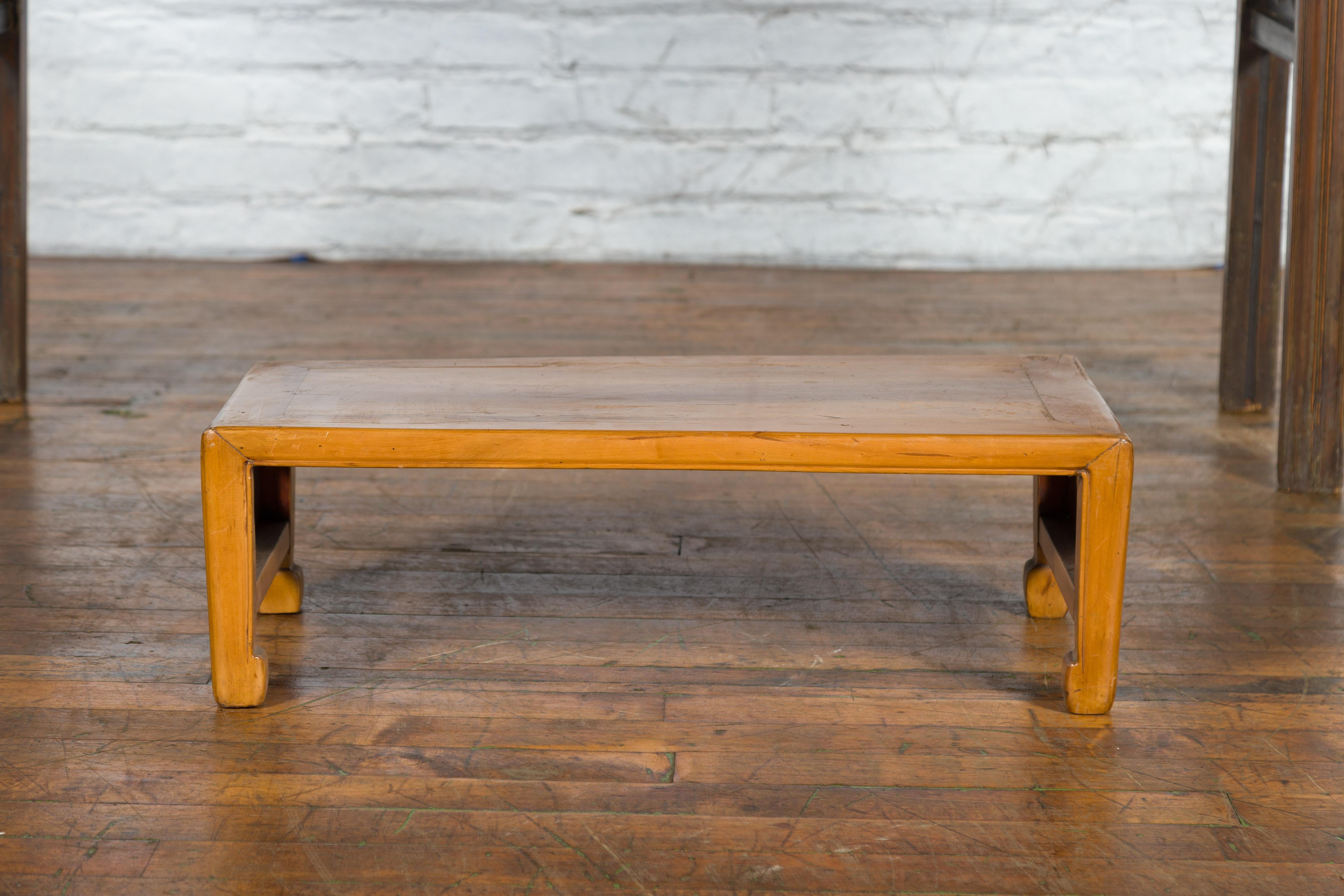 A vintage Chinese low kang table from the mid-20th century, with pierced sides and horse hoof feet. Created in China during the midcentury period, this low kang table features a rectangular top with central board, sitting above four straight legs