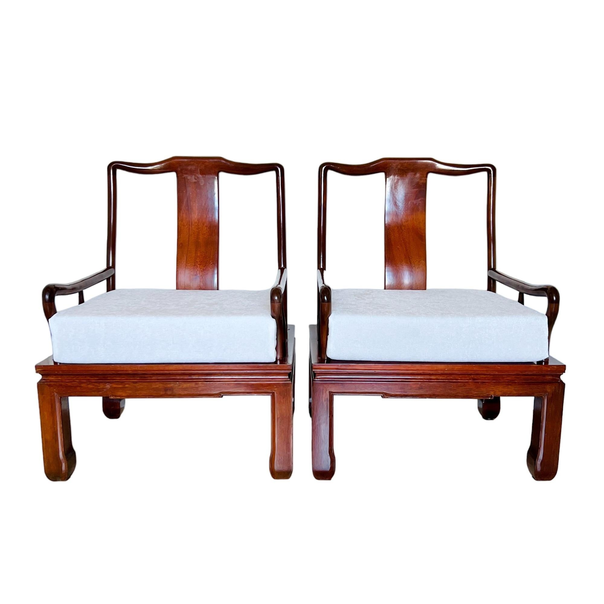 A vintage pair of Chinese Ming style lacquered wood arm chairs with seat cushions. The chinoiserie design features a splat back, low arms with tapered curved middle supports and squared legs with chow feet. The seat cushions are covered in white