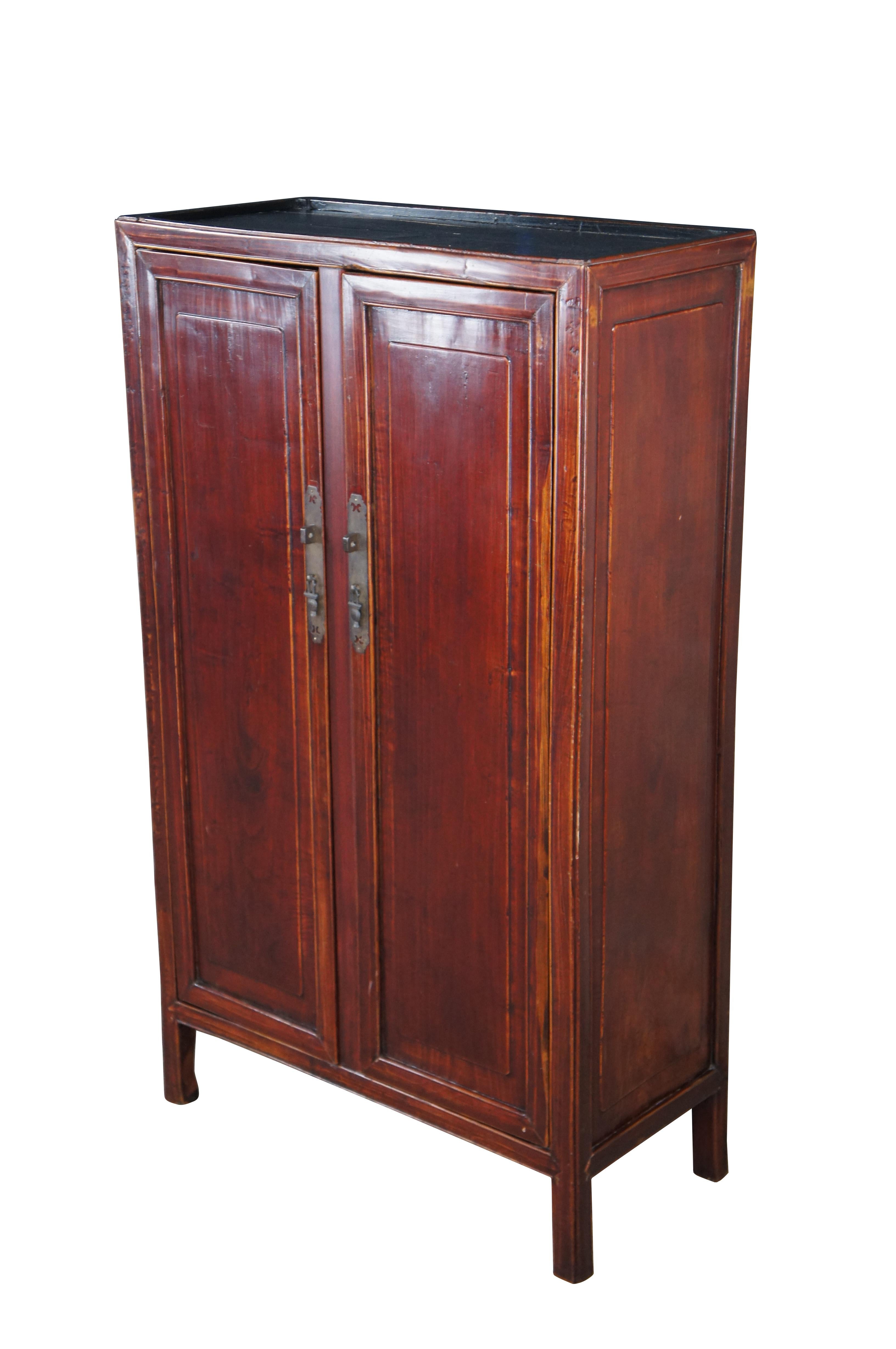 Vintage Chinese Chinoiserie Ming style wedding cabinet / cupboard / armoire / wardrobe.  Made of  Elm featuring a dark red / brown lacquered finish with two doors that open to reveal three shelves / storage areas and two drawers.

Dimensions:
29.5