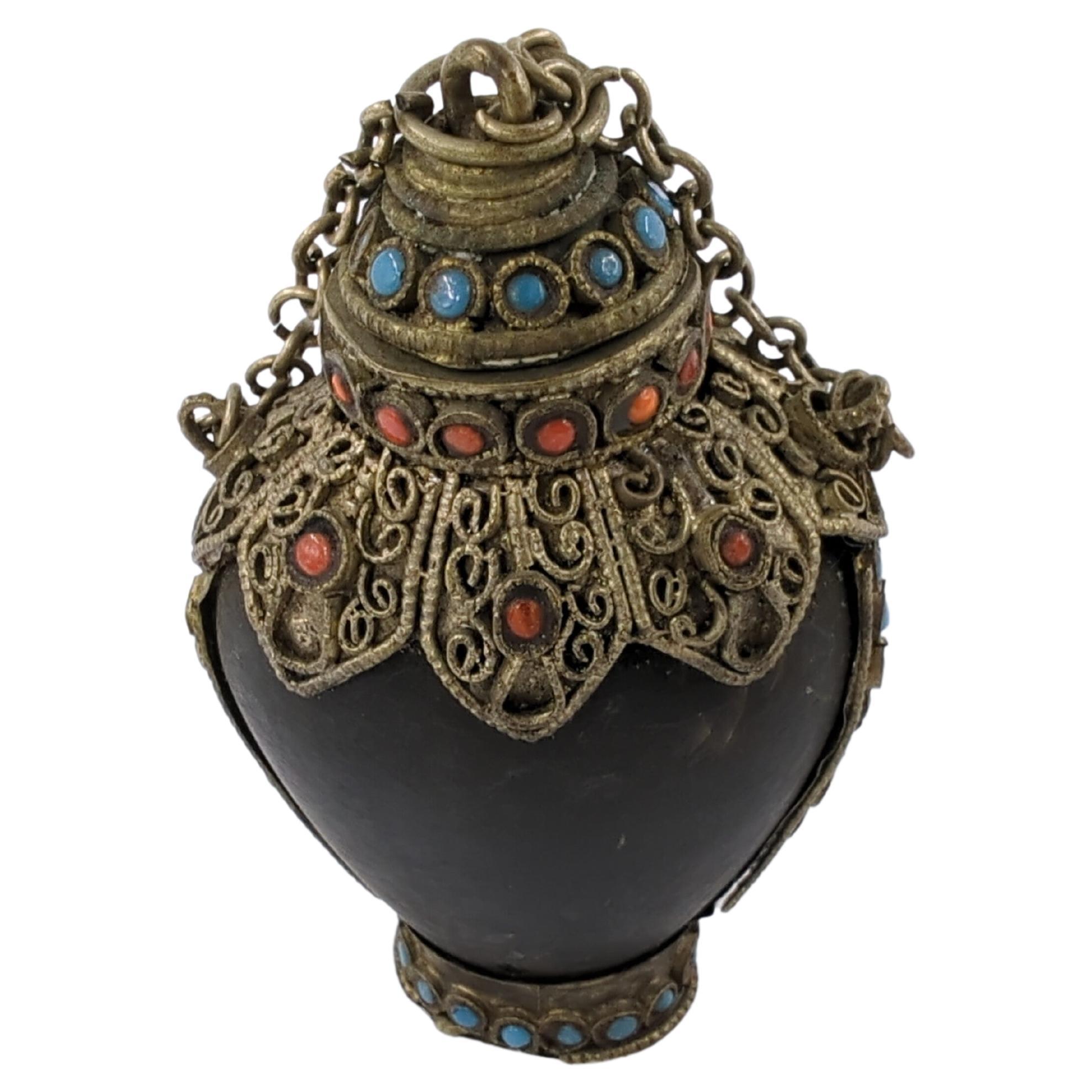 A vintage Mongolian snuff bottle, with silver filigree work and inlaid blue and red paste gems, having a chained matching stopper with silver spoon.

weight: 64 Grams
circa: 20th Century