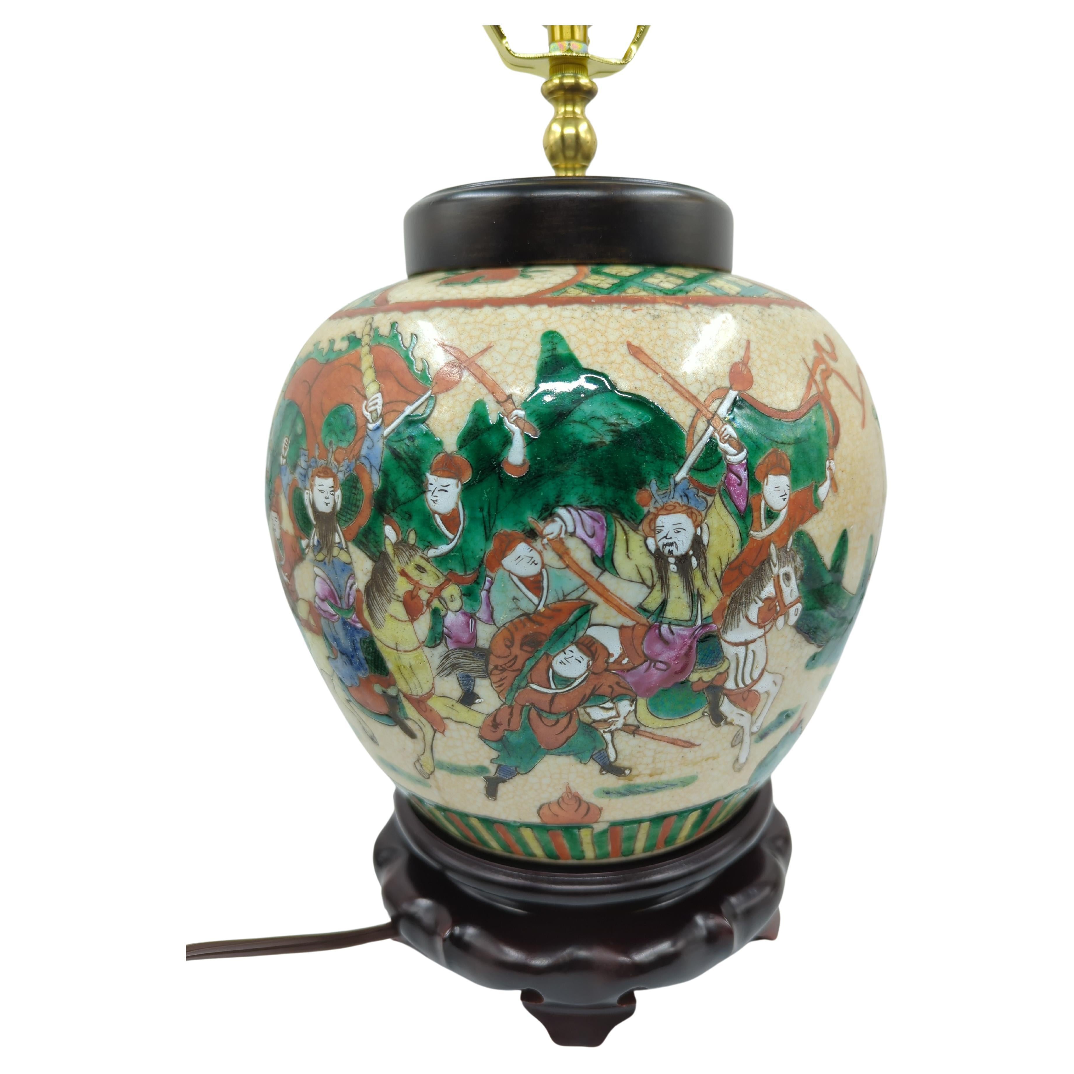 Vase ovoïde en porcelaine chinoise vintage à glaçure craquelée de style Nankin, décoré en famille rose de figures de guerriers dans une scène de bataille, électrifié et transformé en lampe sur un socle en bois.

Prise E26
Taille totale :  H : 17