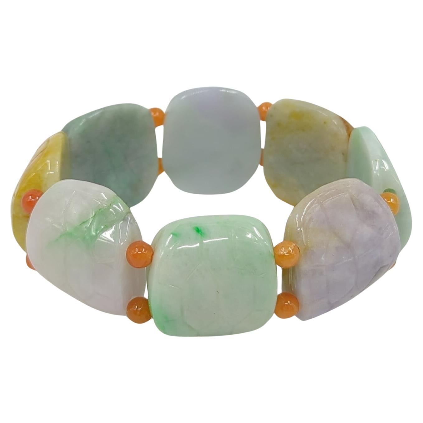 Vintage Chinese hand carved jadeite bracelet in the form of eight multi colored, carved turtle shells, each connected by two intense orange jadeite beads to form a hefty and flexible bracelet (strung with elastic cord), of 10