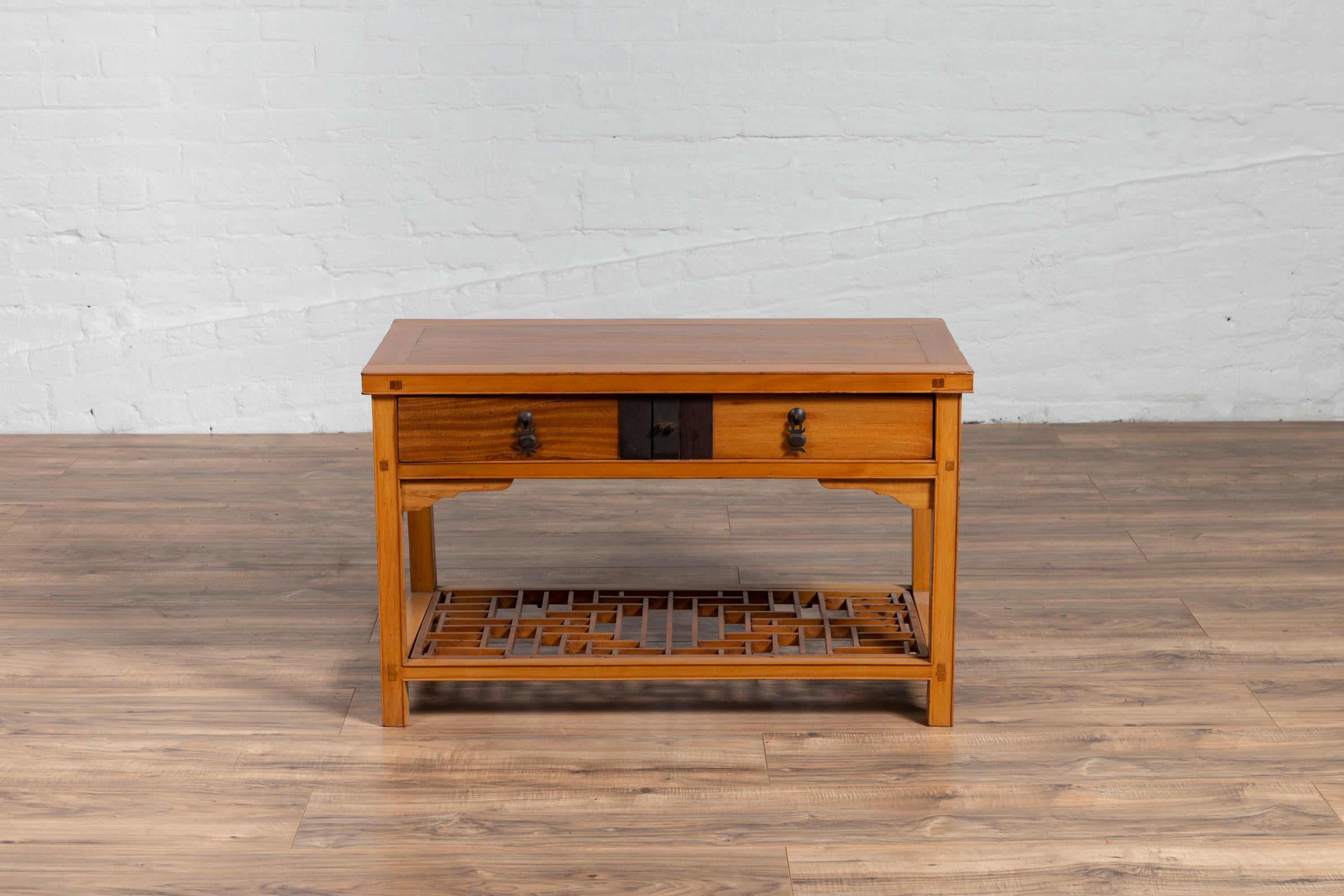 A Chinese vintage natural wood side table from the mid-20th century, with two drawers and 'crackled ice' shelf. Born in China during the midcentury period, this elegant side table features a rectangular top with central board, sitting above an apron