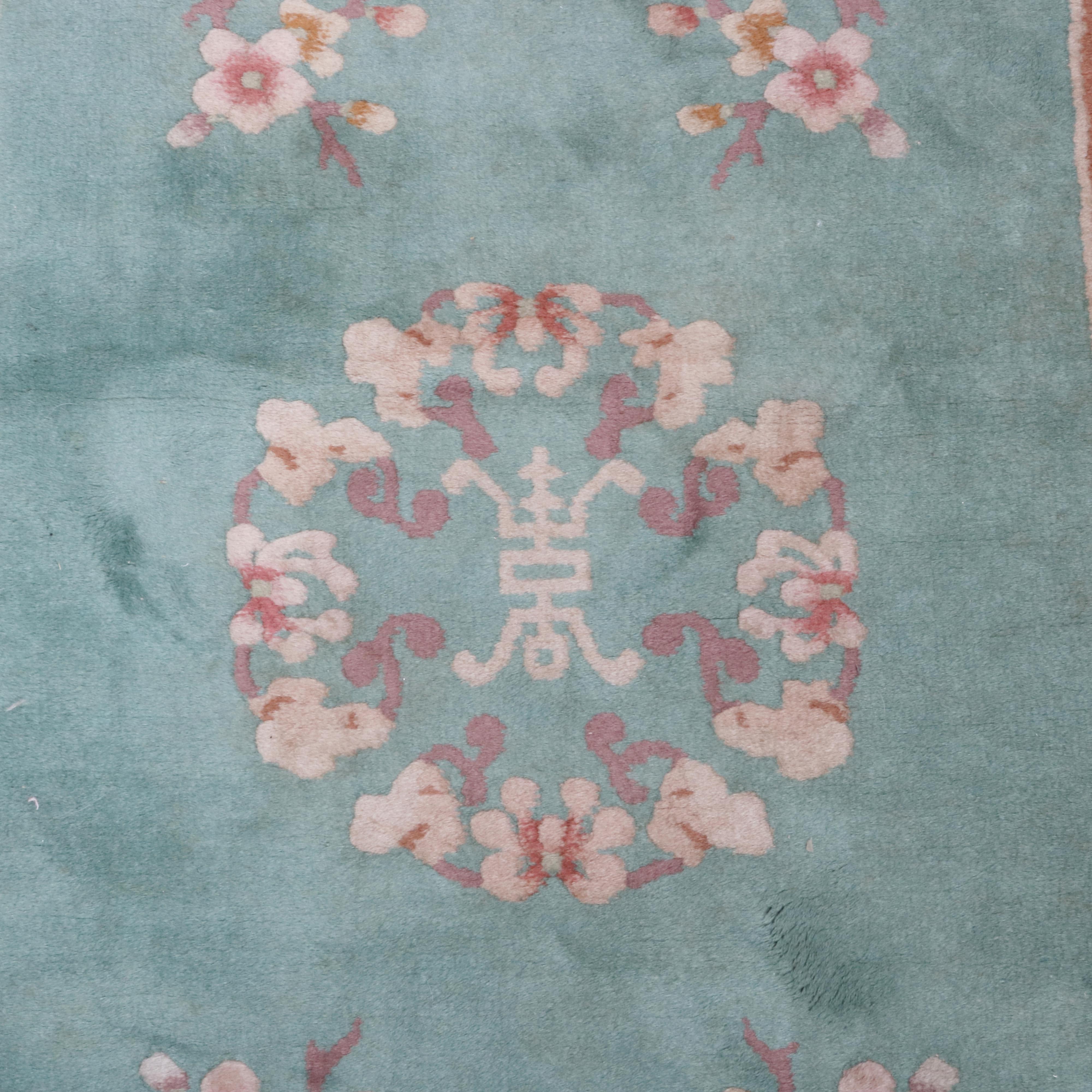 A vintage Chinese Nichols style oriental rug offers wool construction with central floral medallion having Chinese symbol on mint green ground with detached floral spray and cream border, circa 1940

Measures: 78.5