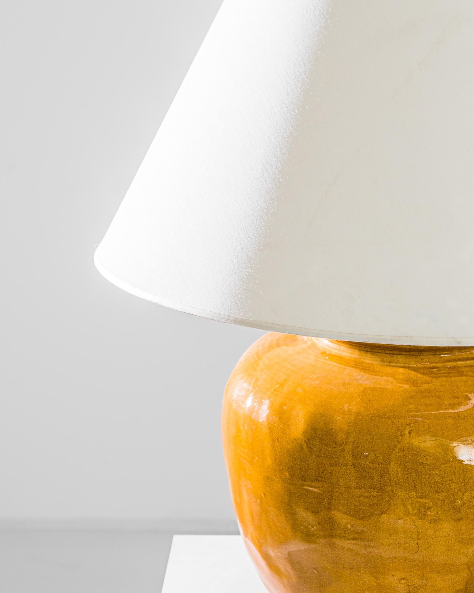 An extraordinary piece to inspire your collection. This vintage Chinese vase has been adapted into a beautiful table lamp. Polished brass meets the seductive warm ochre glaze, enlightening your space with an uncompromising contrast. Textured glazes,