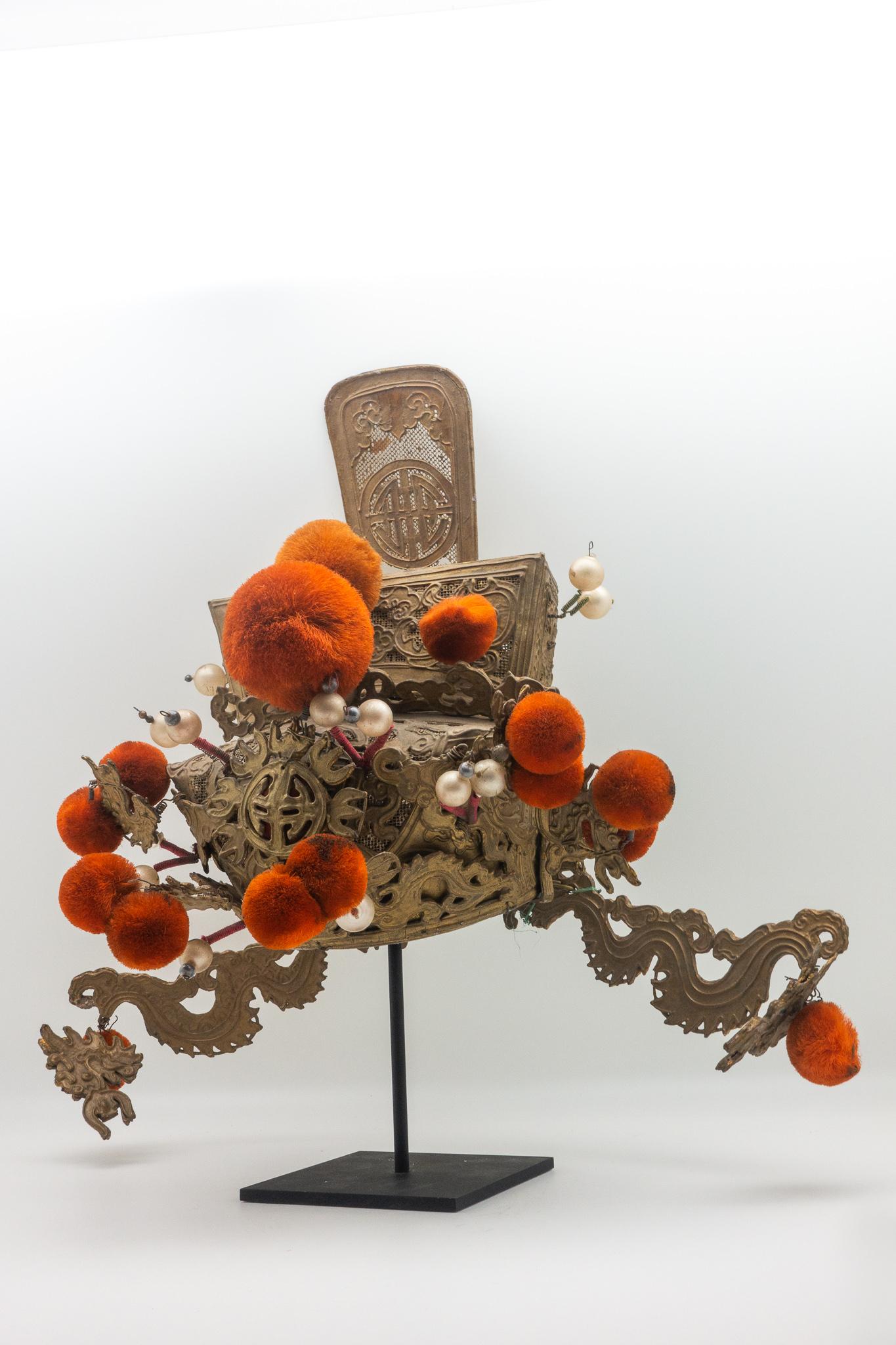 Vintage Chinese opera theatre headdress in gold with orange pom poms.
Early 20th century, mounted on a custom, black painted metal base.