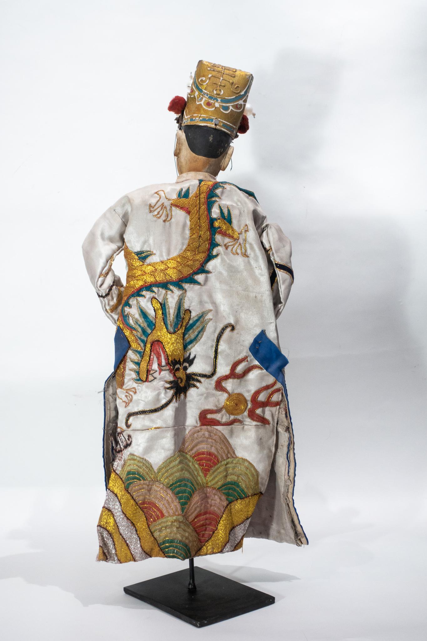 Chinese opera marionette male doll, circa 1920s. The head of this puppet is carved in a soft wood; the feet and hands are also made of wood. The hands can form a closed fist or an open palm by the joint at the level of the fingers. The headdress of