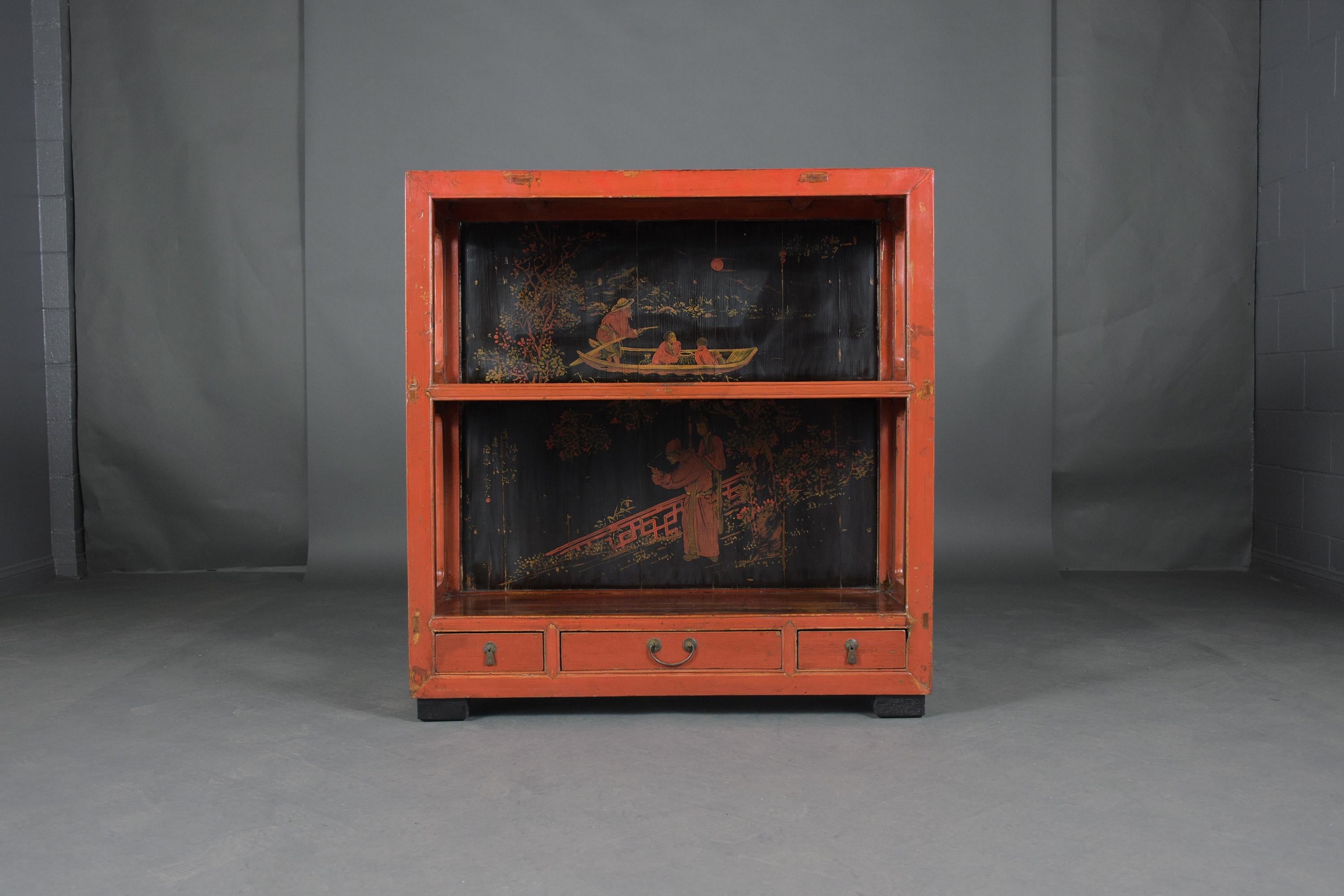 An extraordinary Chinese open cabinet crafted out of teak wood in a good condition. This vintage sideboard features hand-painted details an original red paint color with a unique distressed finish, open shelves, and three bottom drawers. This small