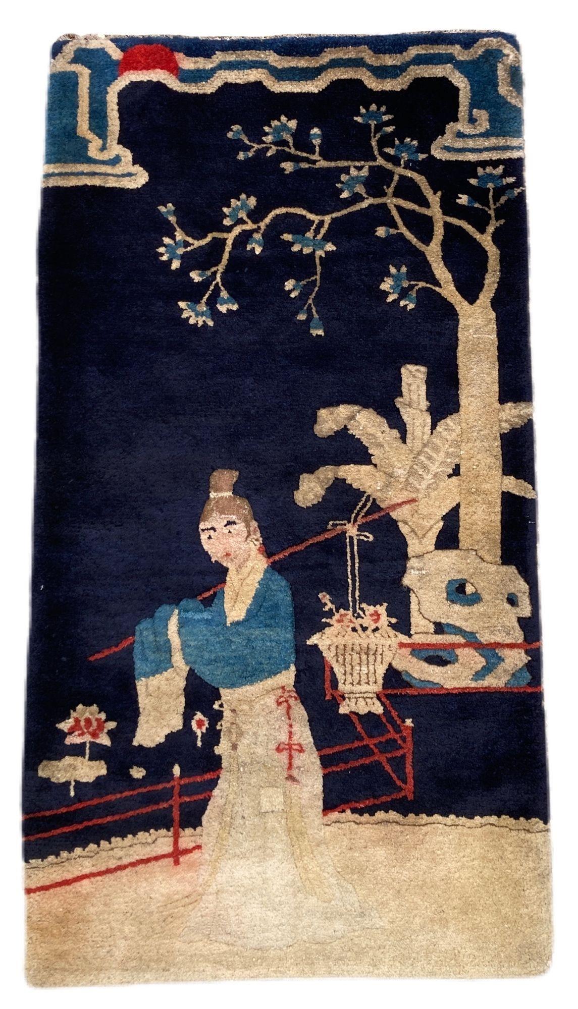 A lovely vintage Pao-Tao rug, handwoven near Beijing in China circa 1940. The design features a girl carrying a basket of flowers beneath a tree on a deep indigo field.
Size: 1.30m x 0.69m (4ft 3in x 2ft 3in).
This rug is in good condition with