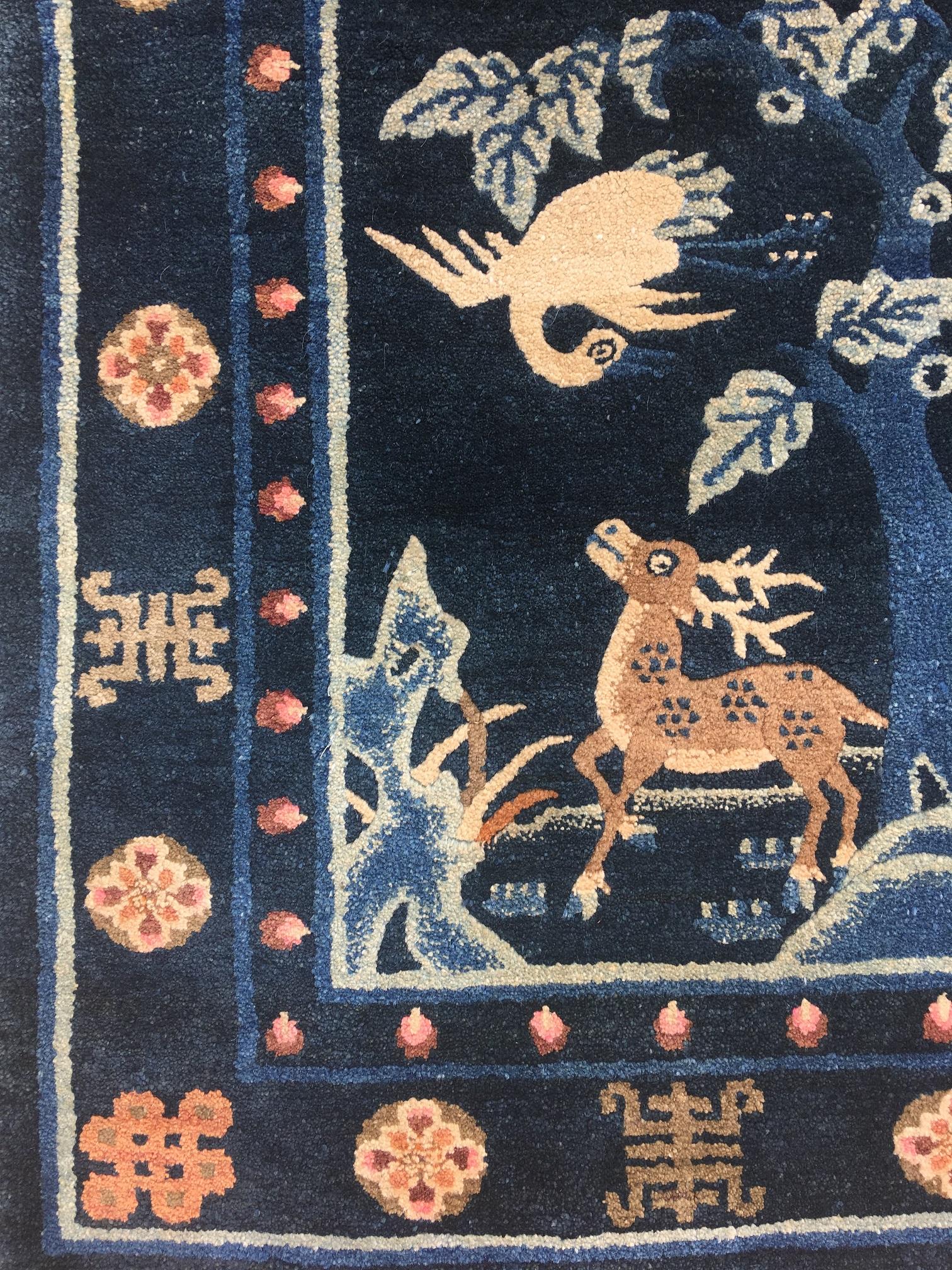 A lovely Pao-Tao rug, handwoven in China, circa 1940 with a mirrored design featuring a crane above a spotted deer, both symbols of longevity, on a navy blue field. Measures: 1.39m x 0.70m.