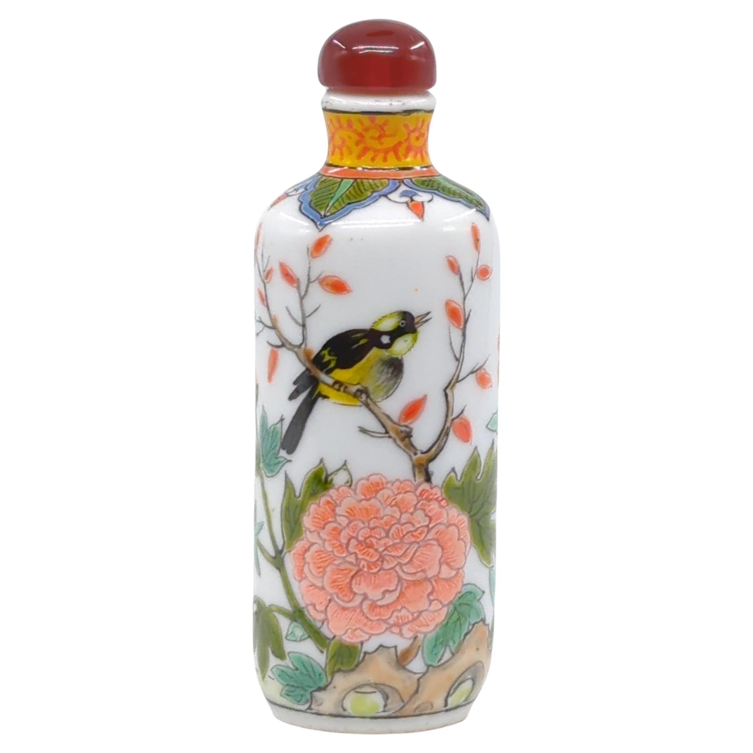 This vintage Chinese snuff bottle from the Republic of China period is a charming example of famille rose porcelain, renowned for its soft, pastel hues. The bottle is hand-painted with a delightful scene of birds amidst a lush garden, complete with