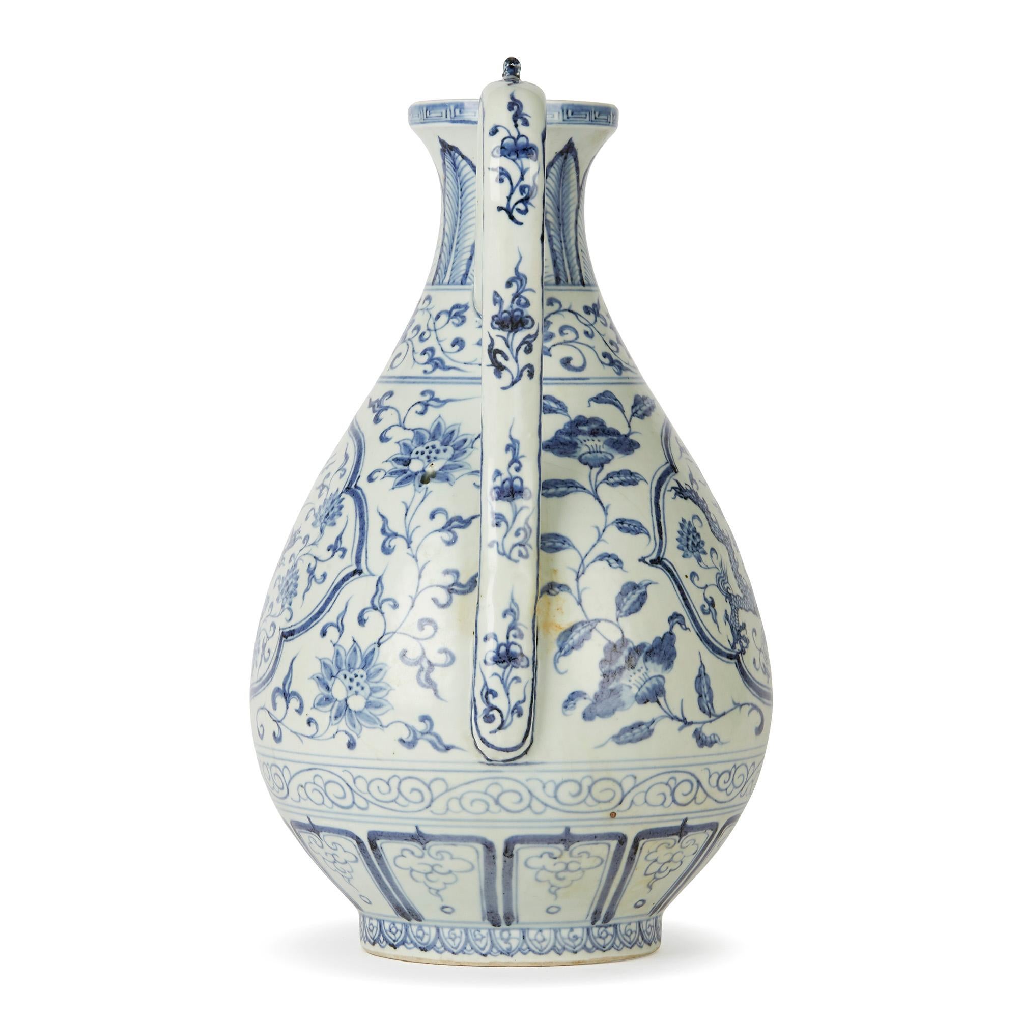A large and impressive vintage Chinese porcelain ewer decorated in underglaze blue with panels one containing a dragon and the other a phoenix bird. The ewer has a pear shaped body with an everted rim with the long spout connected to the body by a