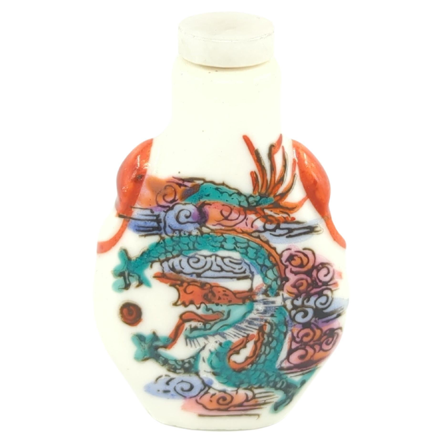 A vintage Chinese porcelain snuff bottle, decorated with a red and green dragon chasing a pearl in blue and pink clouds, with a jade stone stopper

weight: 28 Grams
circa: 20th Century