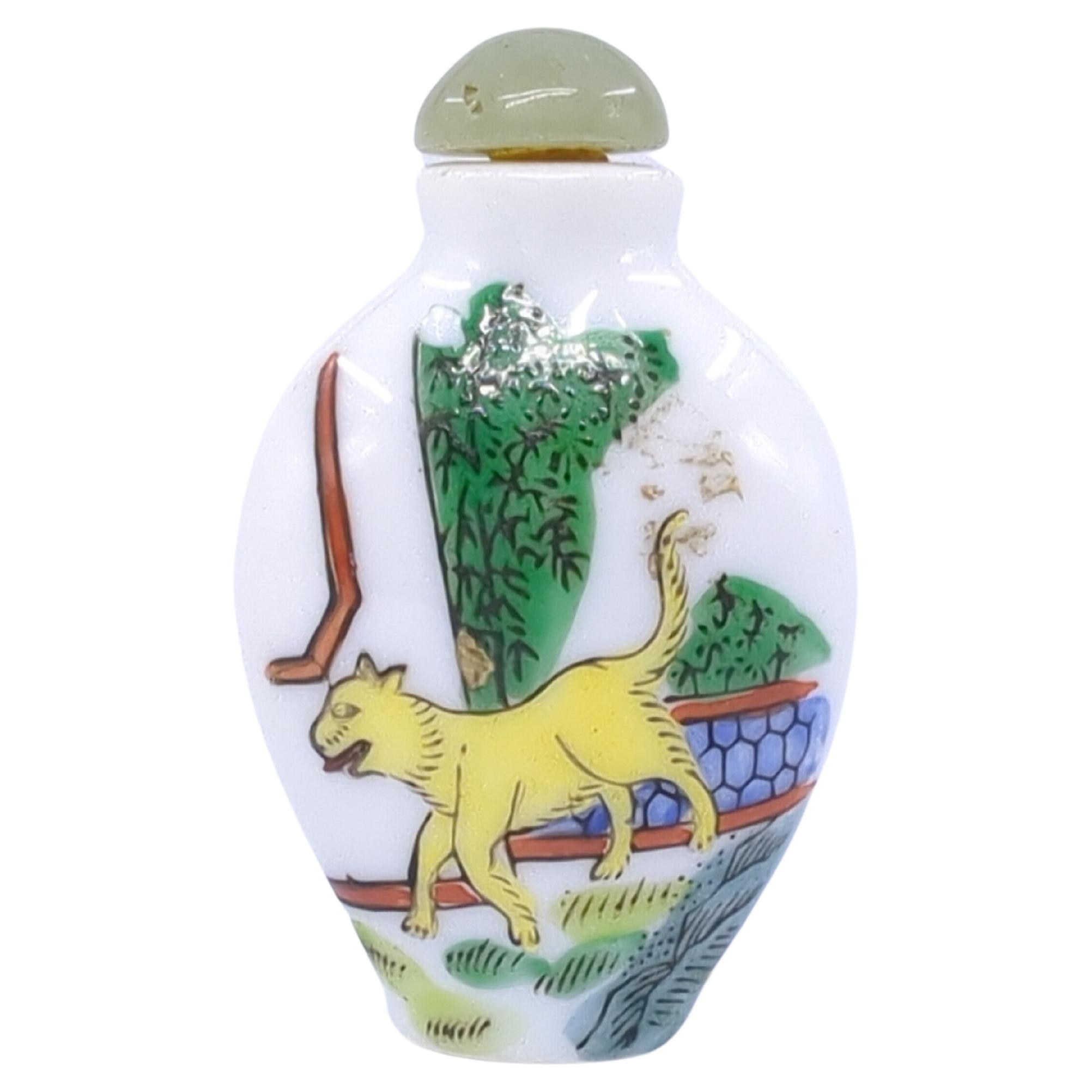 A vintage Chinese porcelain snuff bottle, decorated in fencai with a dog in a garden court yard scene to each side, a three character red 