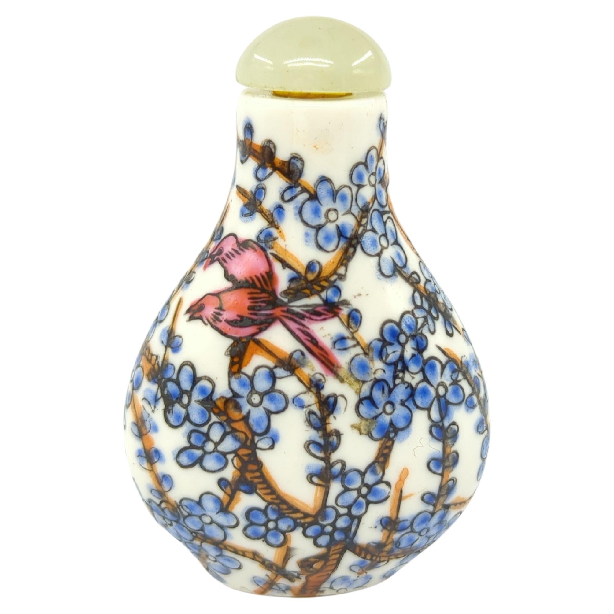 A vintage Chinese porcelain snuff bottle, decorated in fencai with a pair of red birds in  flowering tree branches, with a jade cabochon stopper, and a four character 